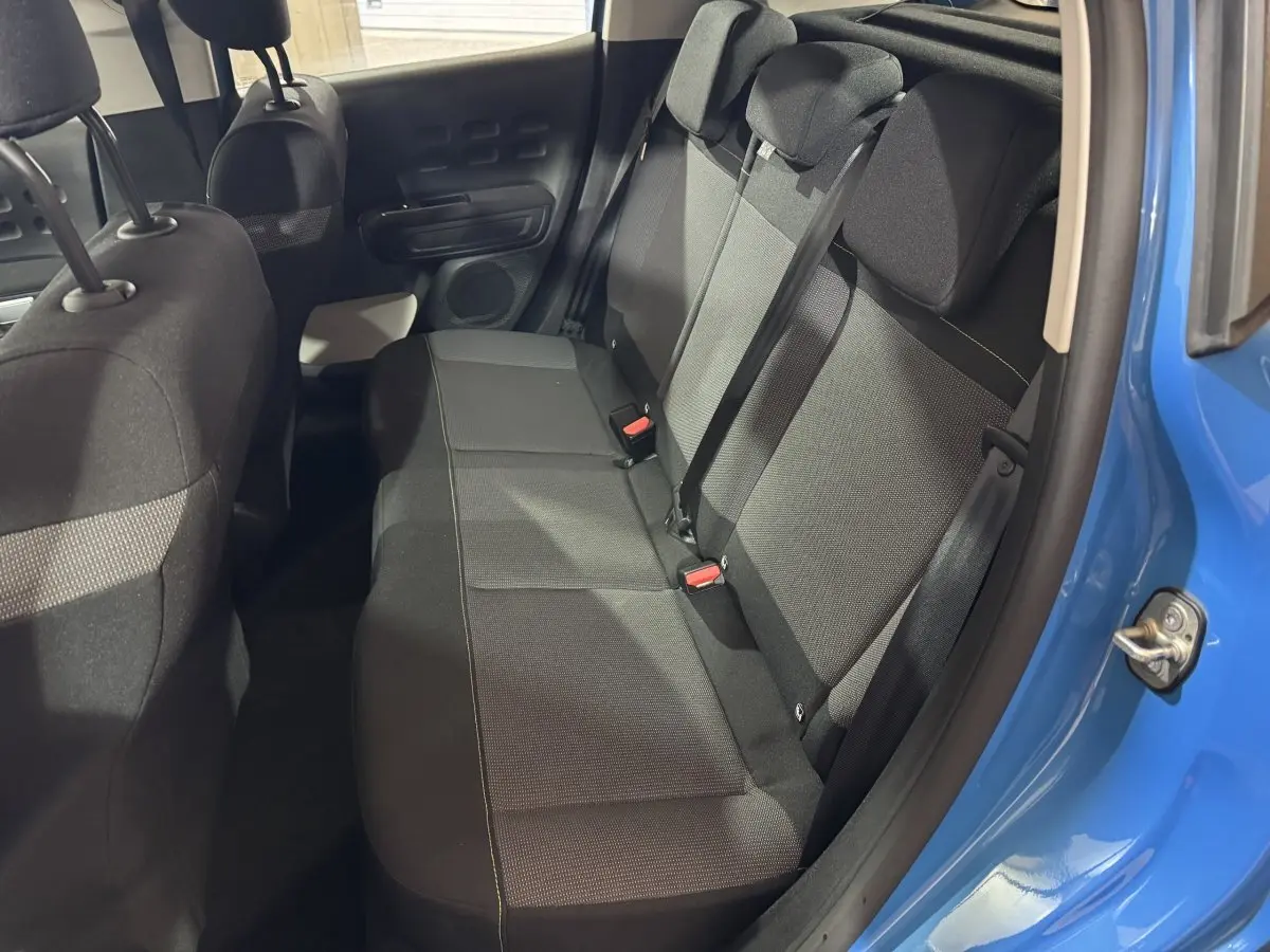 Vue intérieure côté droit sur la banquette arrière noire d'une Citroën C3 bleu 2018 avec ceinture de sécurité attachée.