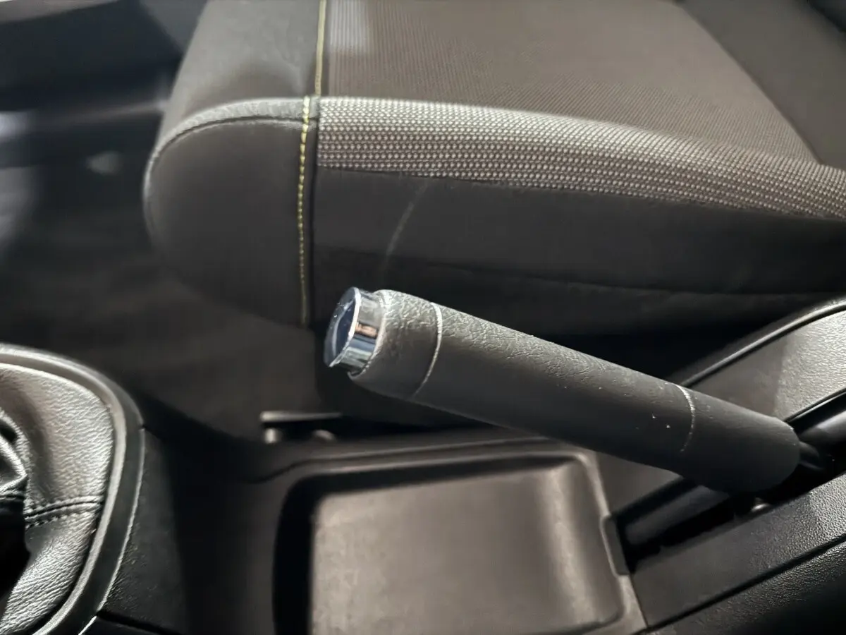 Gros plan sur le frein à main en cuir noir et la partie du siège avant gris foncé de la Citroën C3.