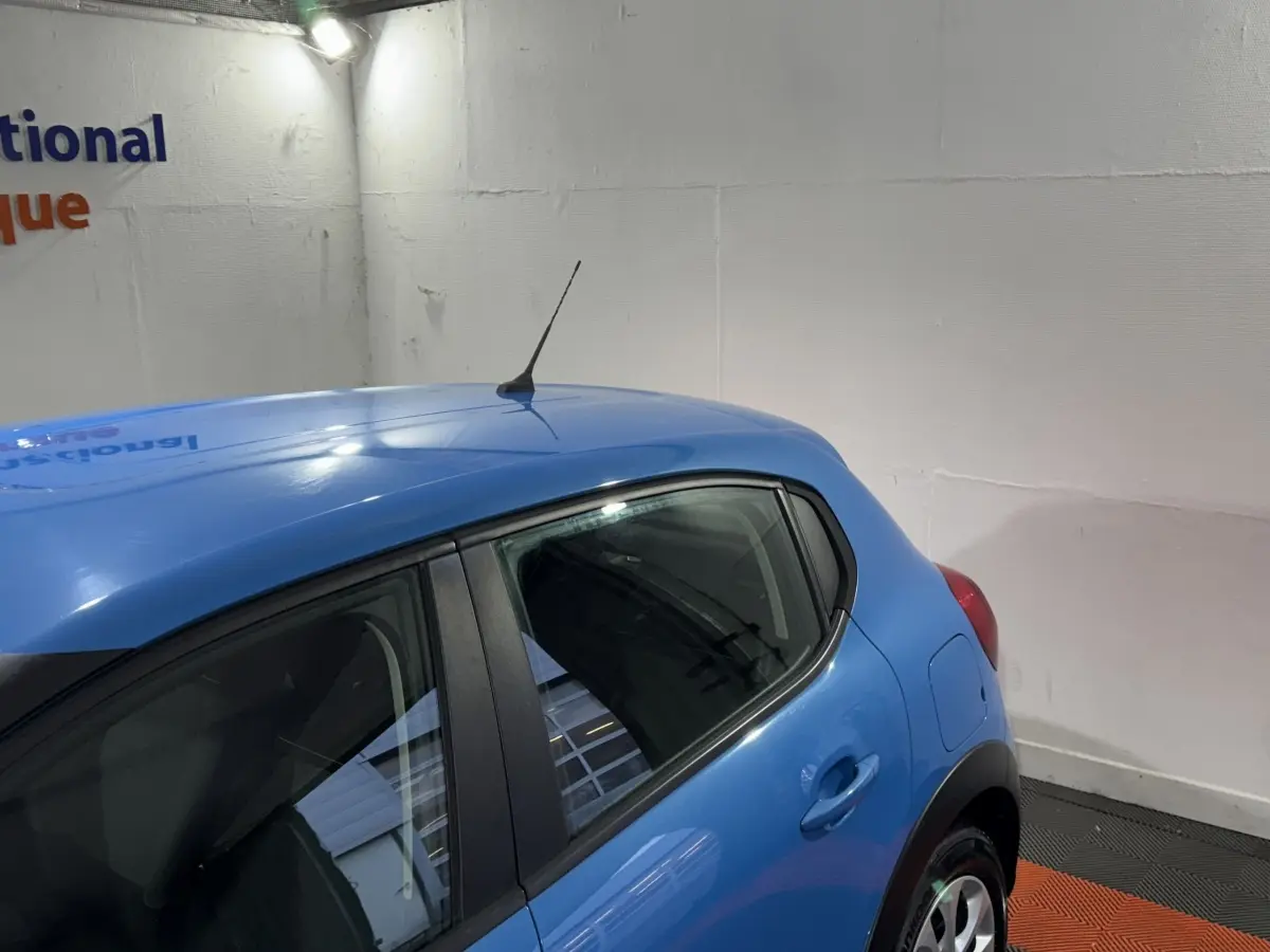 Vue arrière côté droit d'une Citroën C3 bleu vif avec antenne de toit et poignées de porte ton caisse.