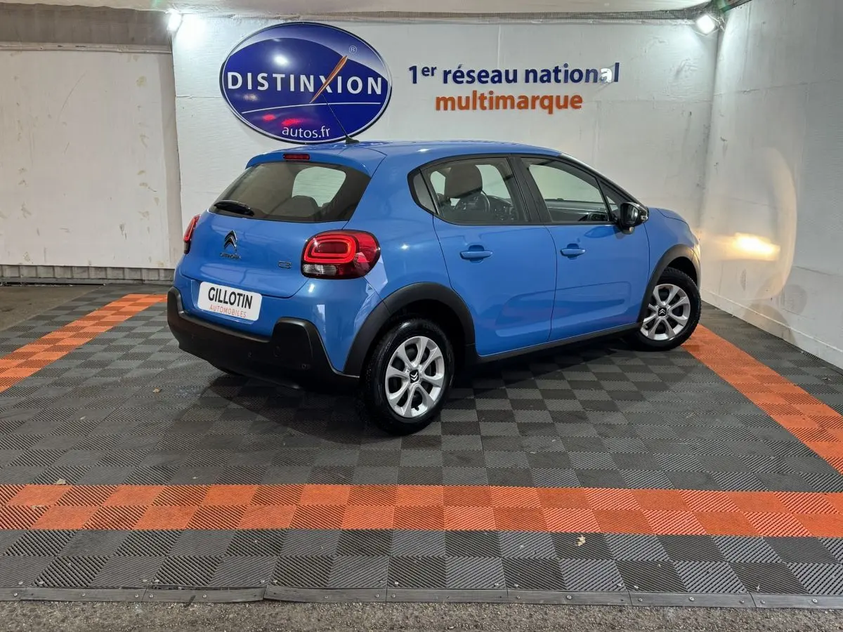 Citroën C3 bleu vue 3/4 arrière droit dans un showroom avec logo Distinxion en arrière-plan.