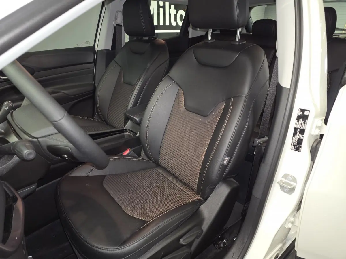 Vue intérieure côté conducteur du Jeep Compass 2024 blanc, sièges avant en sellerie mixte noir et bronze.