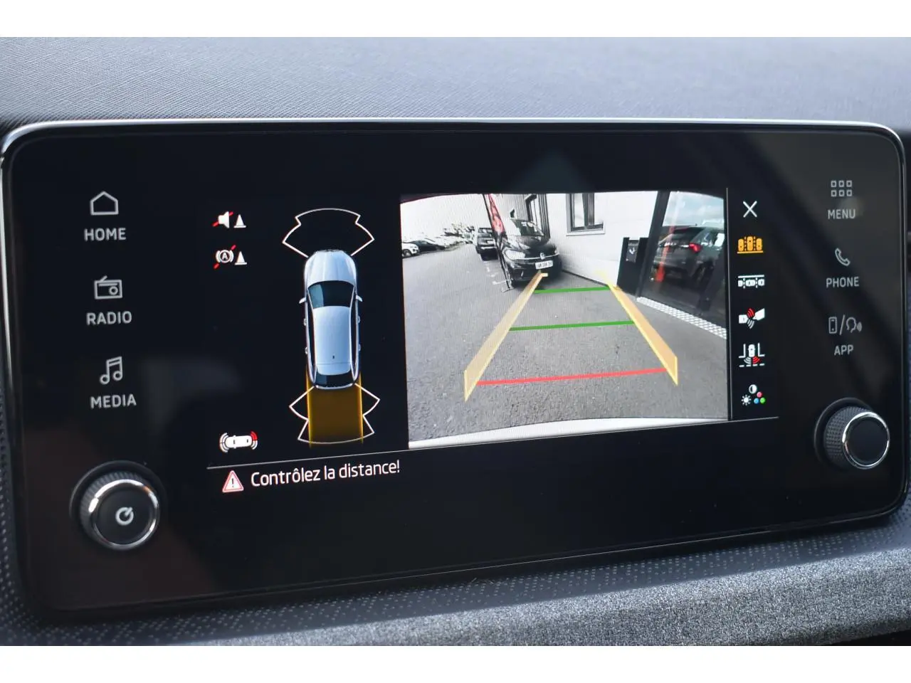 Écran tactile intérieur affichant la caméra de recul et les capteurs de distance du Skoda Scala blanc glacier.