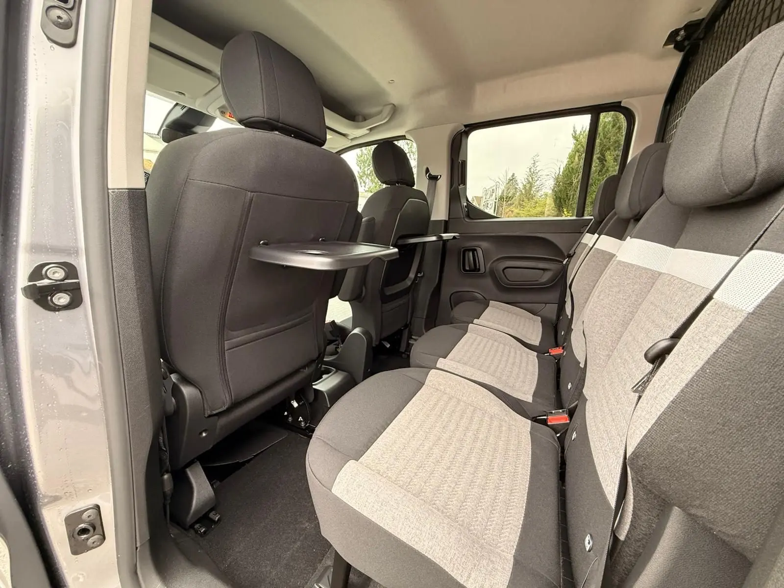 Vue intérieure côté droit du Citroën Berlingo gris Artense 2025, montrant la banquette arrière et les tablettes rabattables.