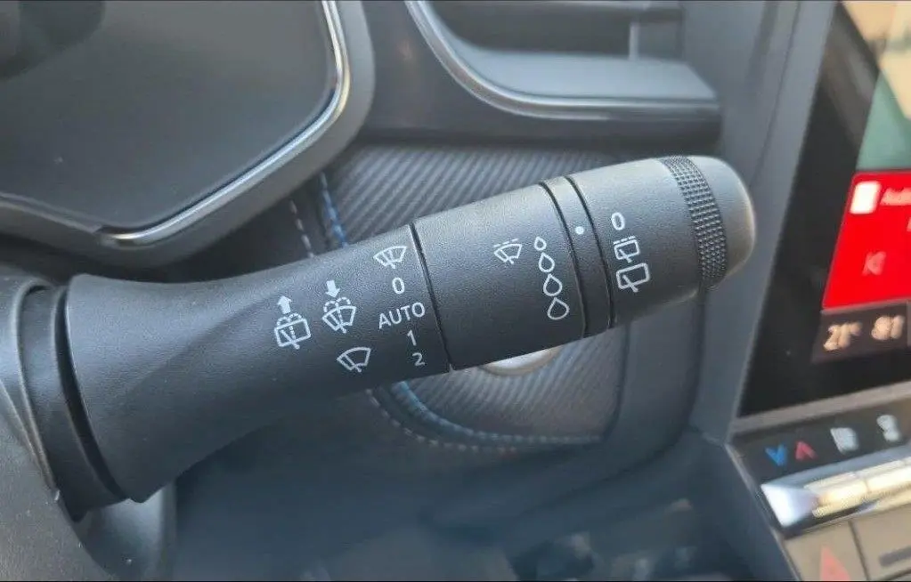 Gros plan sur la commande des essuie-glaces du Renault Captur E-Tech hybride 2025, intérieur noir avec surpiqûres bleues.