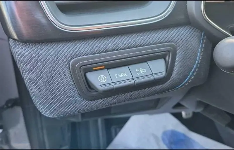 Gros plan sur les commandes du tableau de bord côté gauche du Renault Captur E-Tech gris rafale, avec bouton E-SAVE et frein à main électronique.