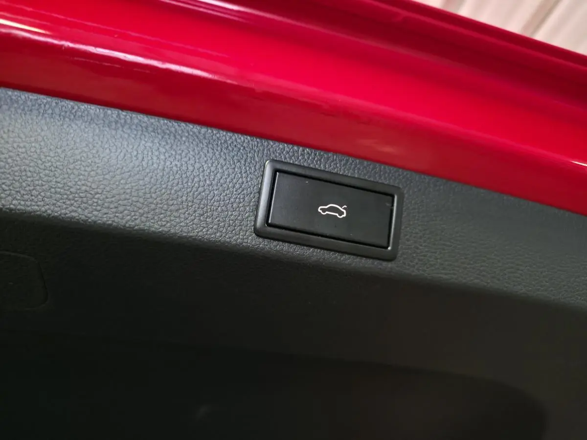 Bouton d'ouverture du hayon noir sur intérieur de coffre rouge d'un Skoda Karoq Style 2018.