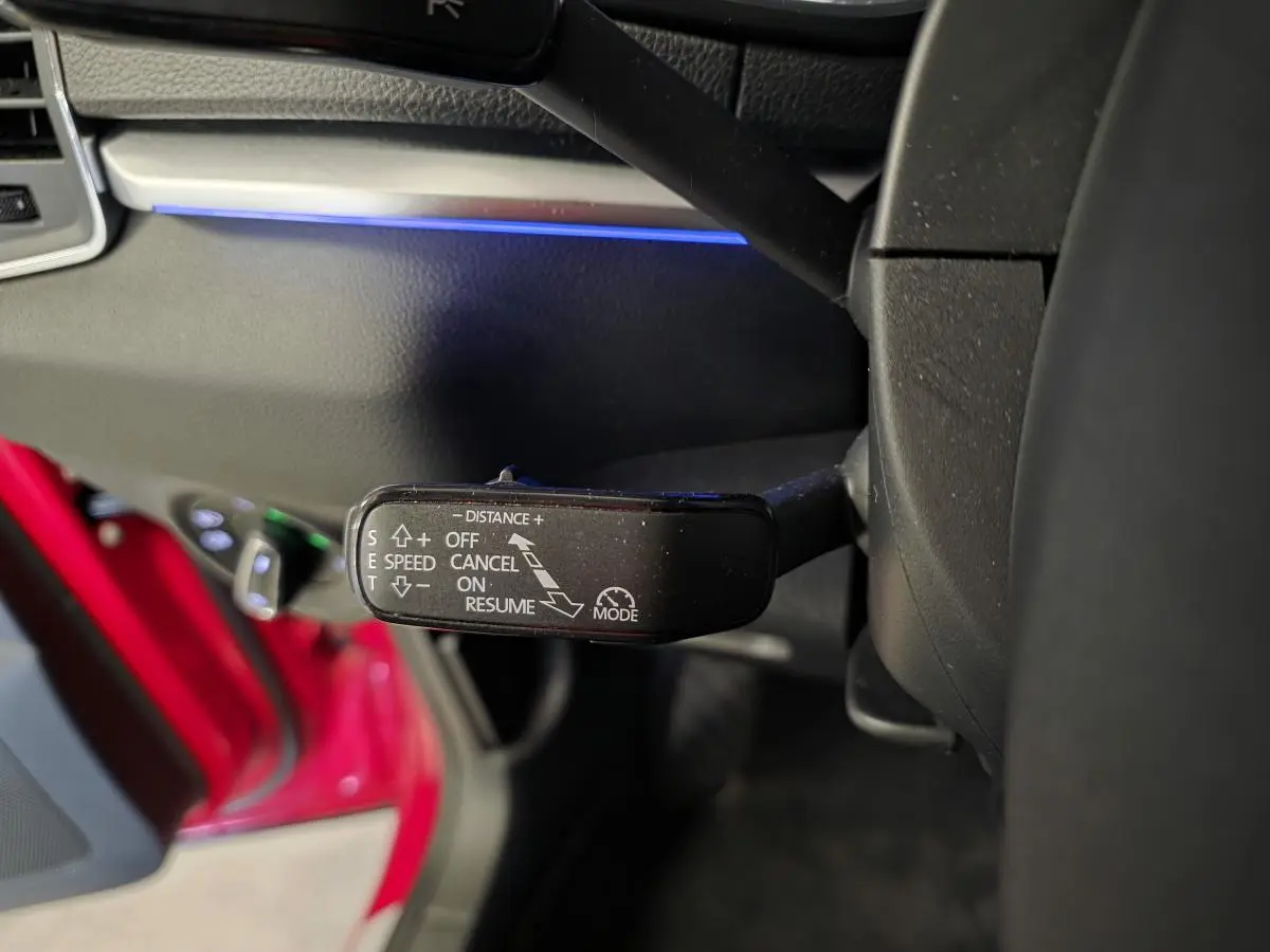 Le levier de commande du régulateur de vitesse dans l'habitacle côté gauche d'une Skoda Karoq rouge.