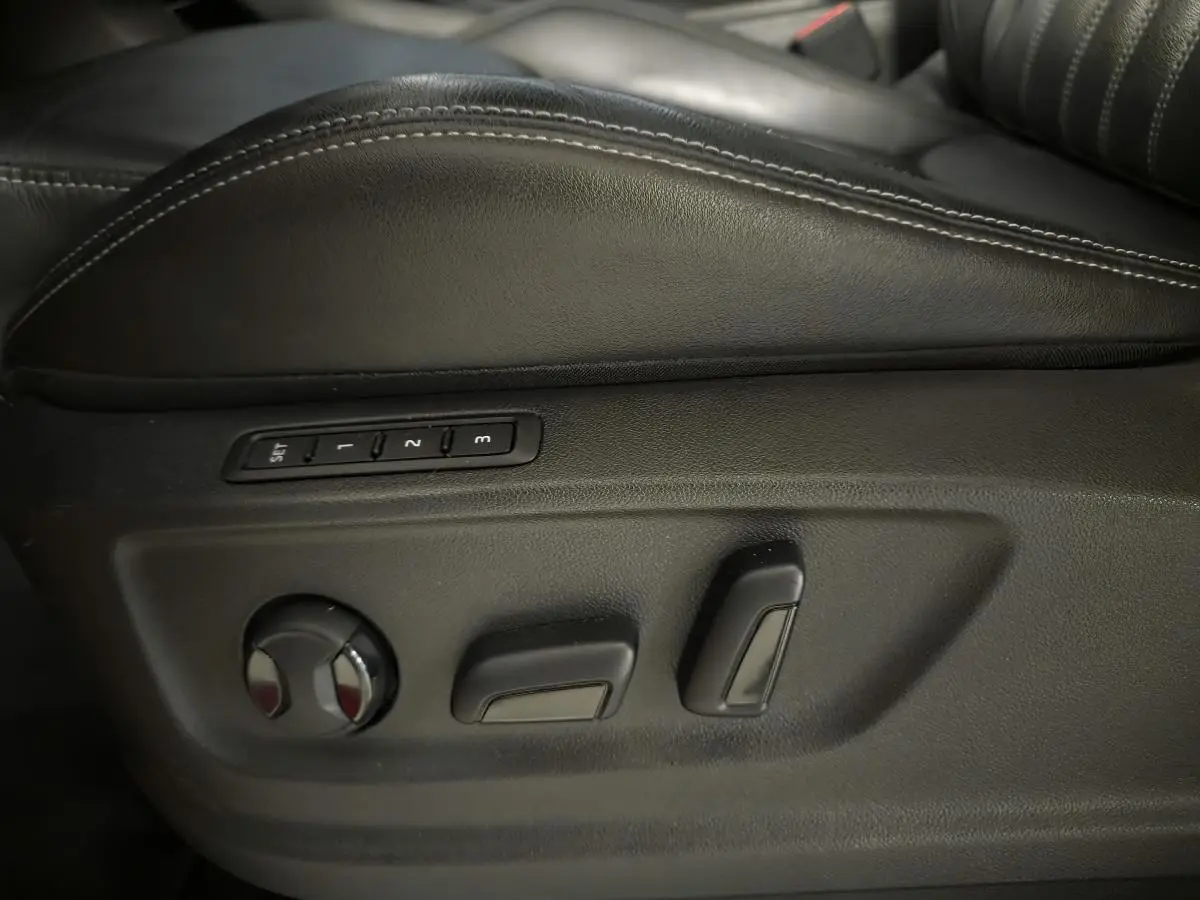 Gros plan sur les commandes de réglage électrique du siège conducteur en cuir noir du Skoda Karoq rouge.