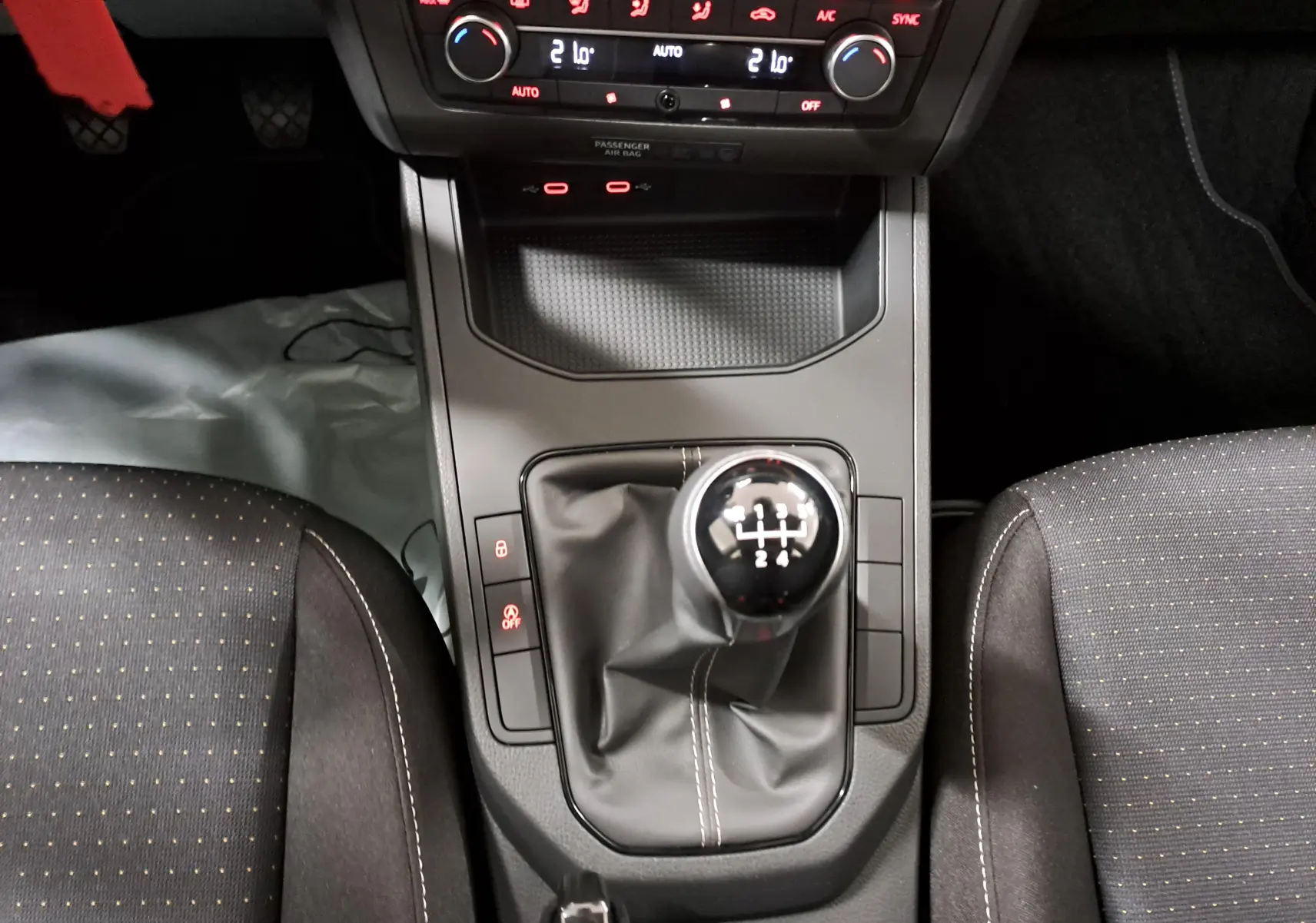 Gros plan sur la console centrale de la SEAT IBIZA 2024 noir minuit, mettant en valeur le levier de vitesse manuel et les commandes de climatisation.