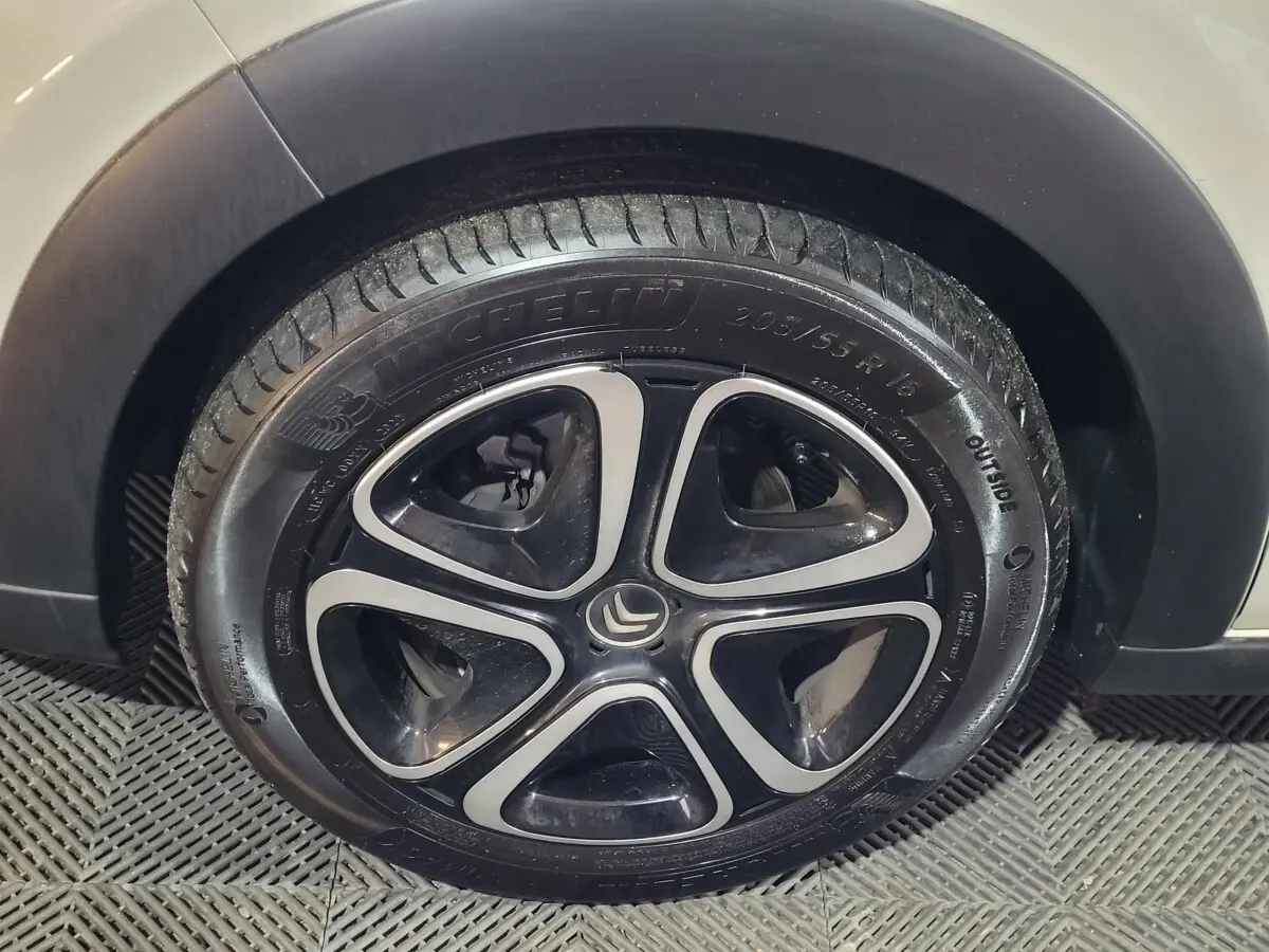 Gros plan sur la roue avant droite d'une Citroën C3 beige, mettant en valeur la jante noire et argentée au design moderne.