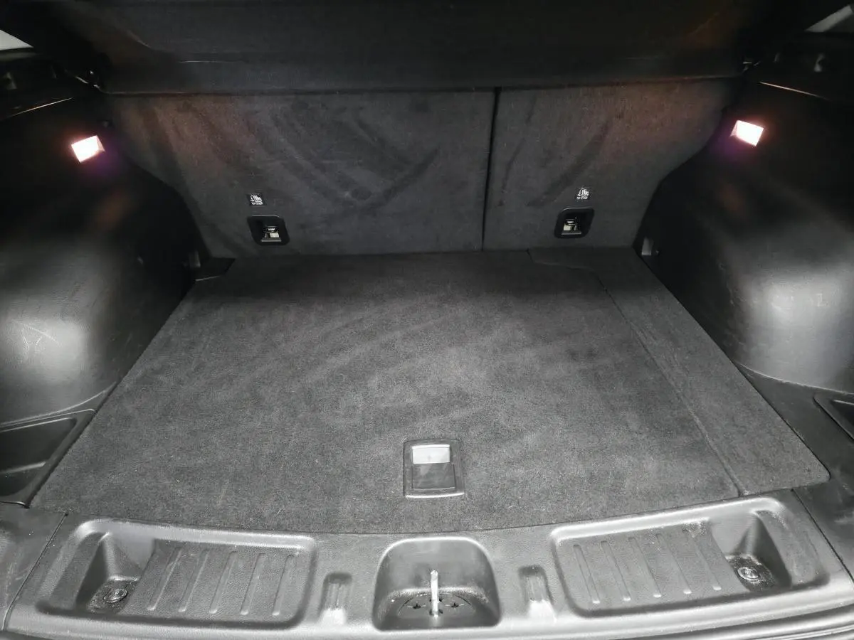 Coffre noir spacieux de Jeep Compass 2024, vue intérieure arrière avec éclairage d’ambiance et tapis en tissu.
