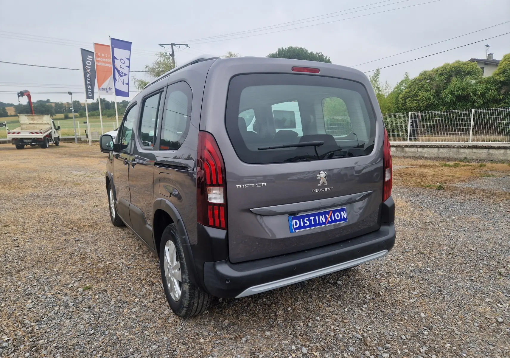 Vue arrière du coffre ouvert d'un Peugeot Rifter gris platinium 2019, montrant l'espace de chargement et les sièges arrière.