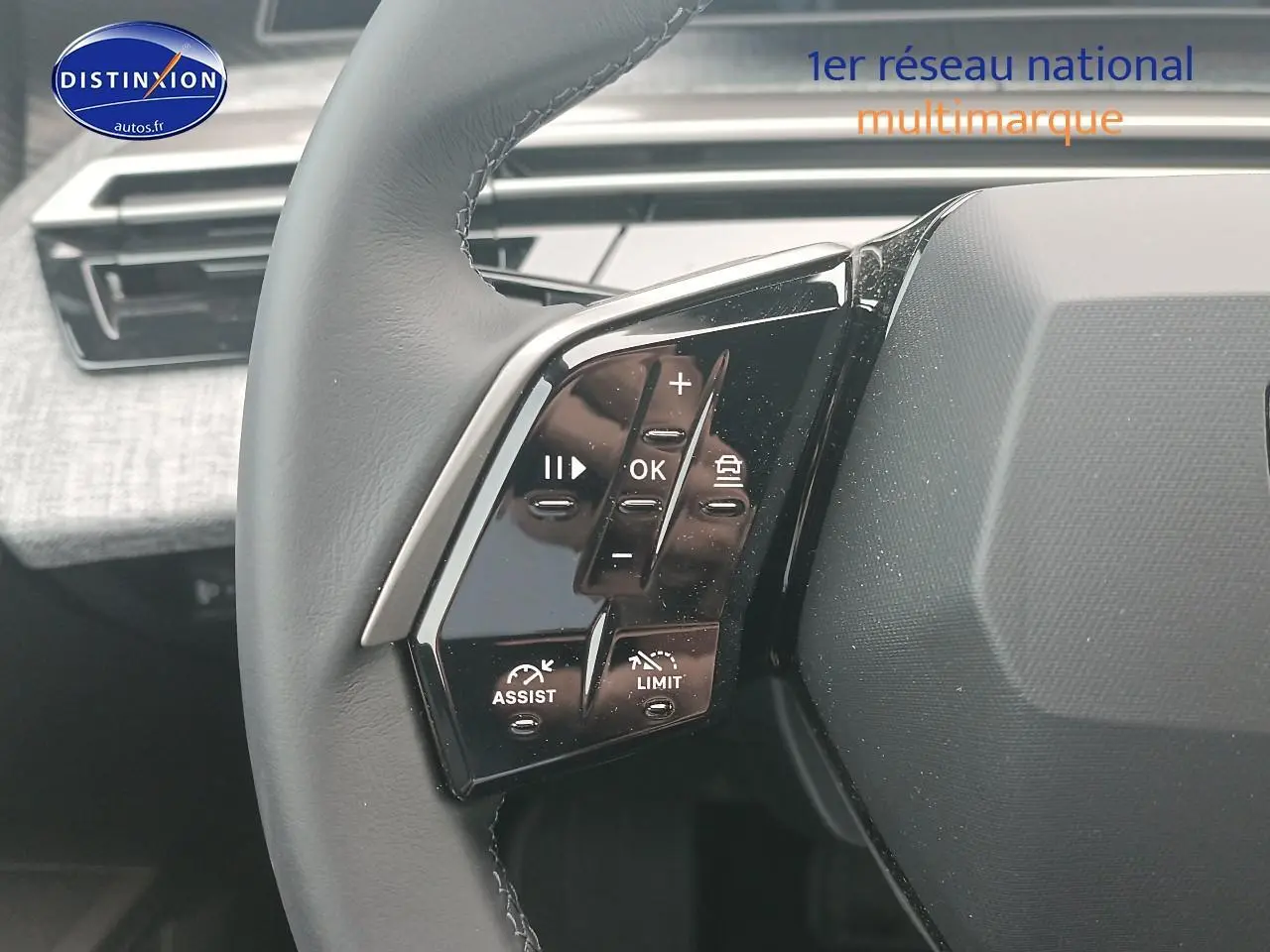 Gros plan sur les commandes gauche du volant cuir du Peugeot 5008 Hybrid 145 allure gris Artense, intérieur moderne.