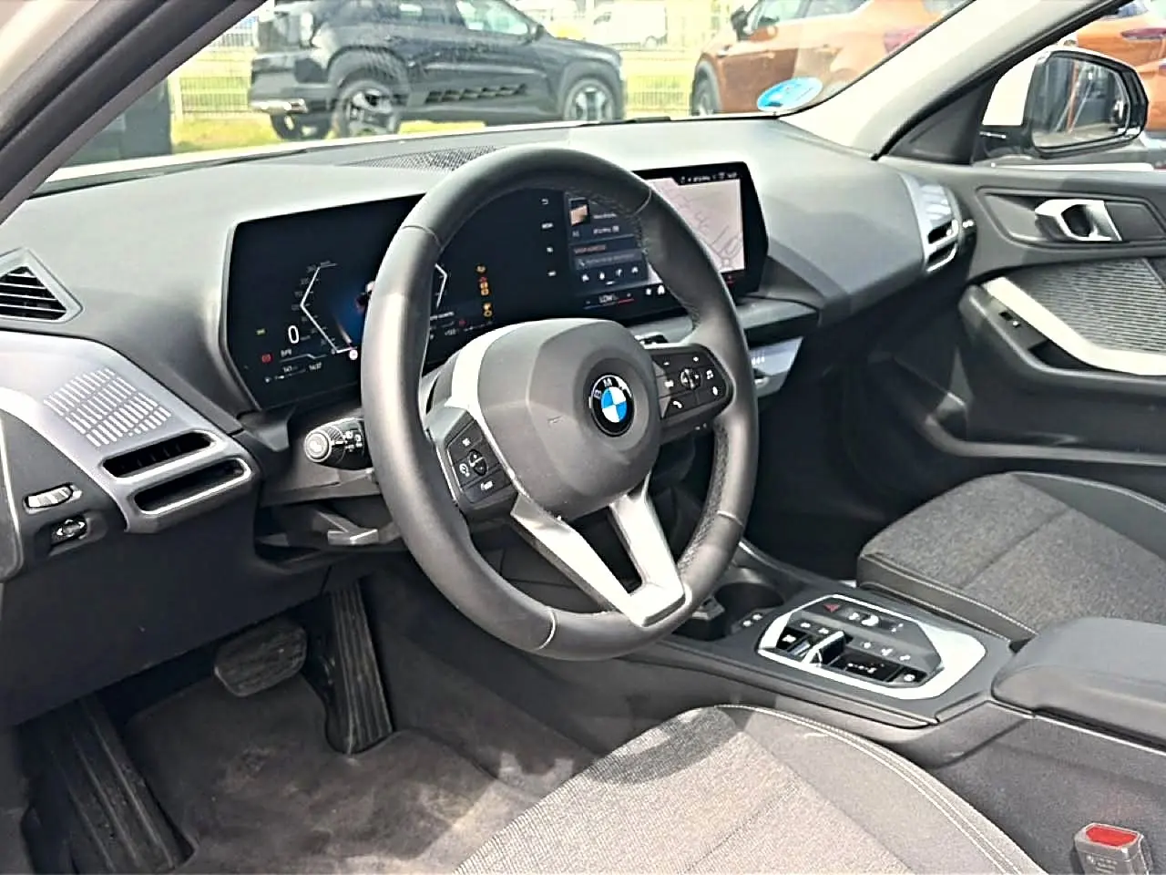 Vue intérieure côté conducteur de la BMW Série 1 120da 2025 avec volant cuir M et écran tactile moderne.
