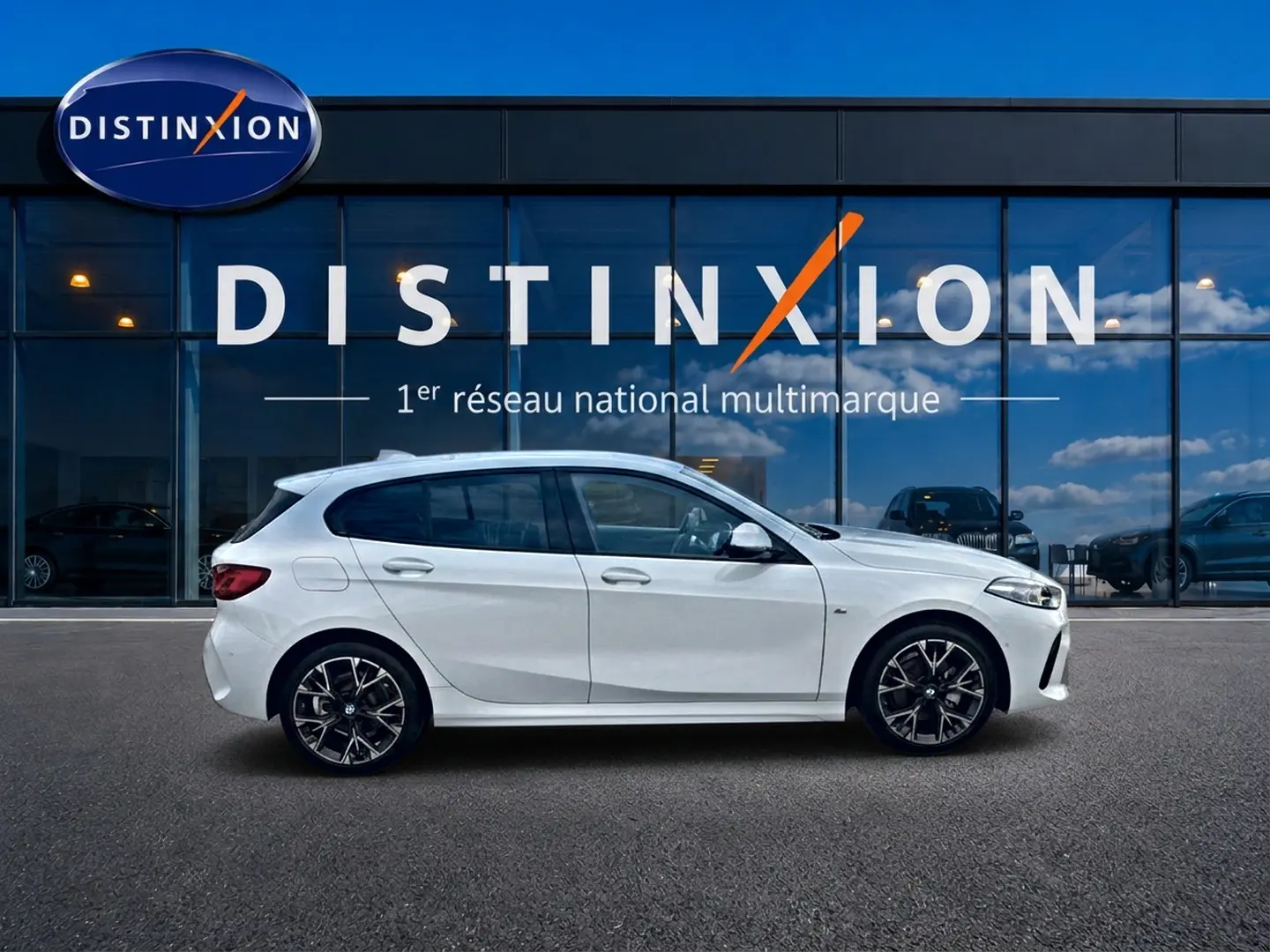 BMW Série 1 blanche vue de profil côté gauche, avec jantes alliage noires et détails M Sport visibles.