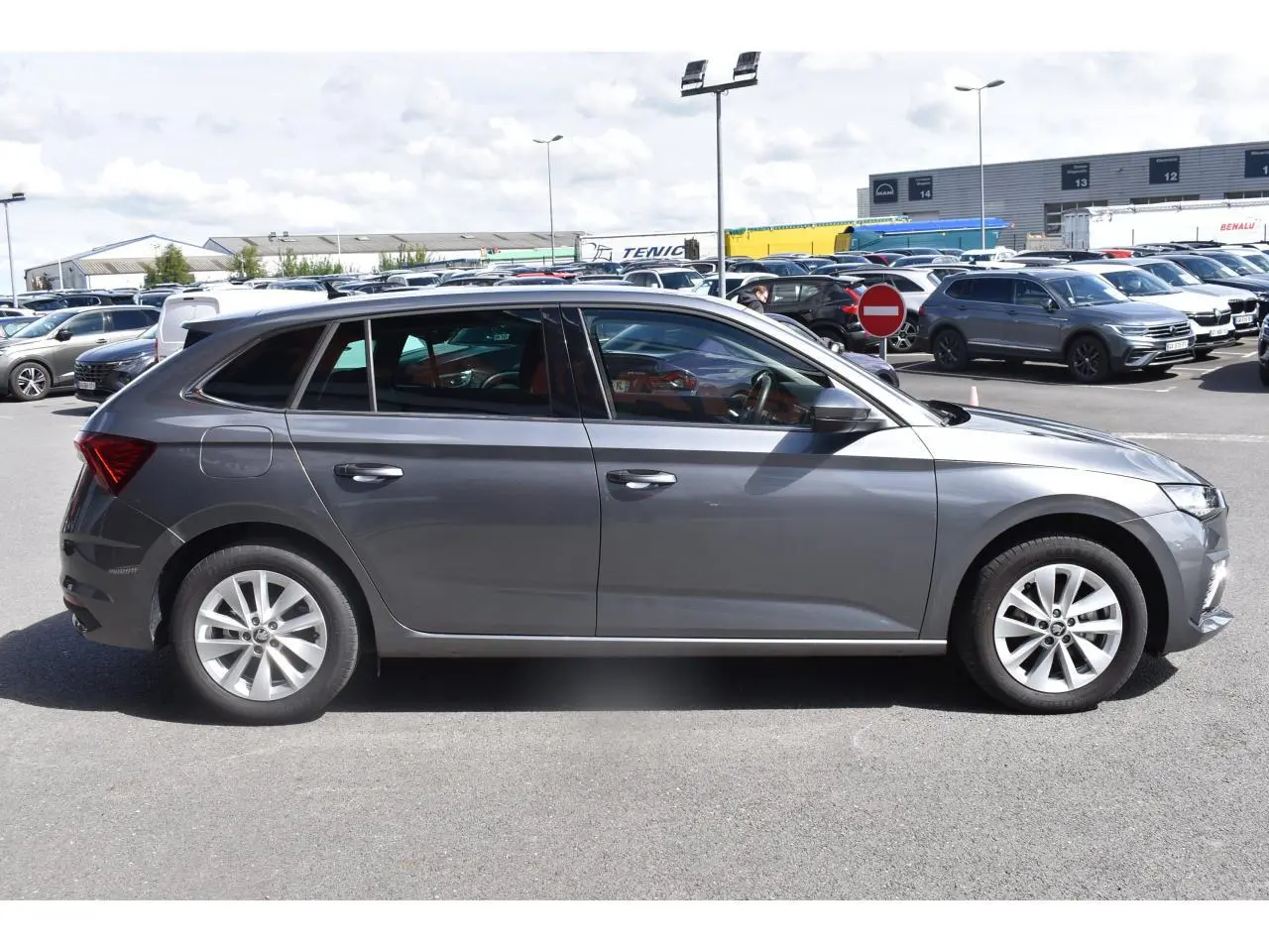 Vue de profil côté gauche d'une Skoda Scala gris graphite avec jantes alliage sur un parking extérieur.