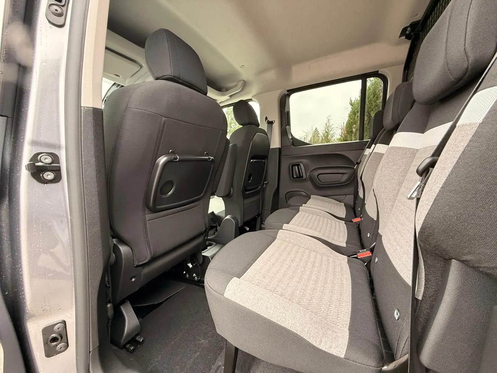 Vue intérieure côté droit sur la banquette arrière grise et noire du Citroën Berlingo Taille M 2025, avec porte ouverte.
