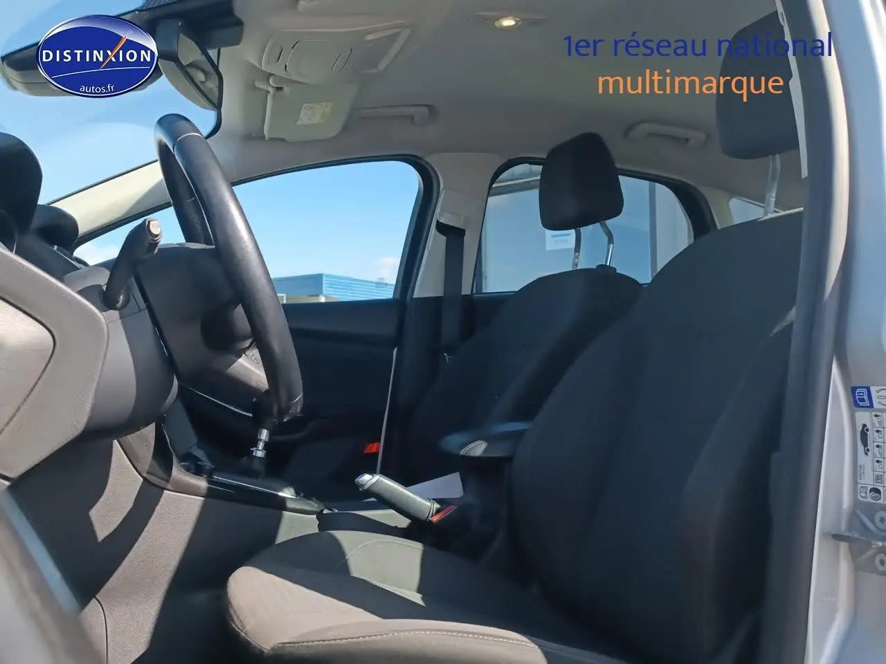 Intérieur noir de la Ford Focus 1.0 Ecoboost 125 Titanium 2017, vue côté conducteur avec volant cuir et accoudoir central.