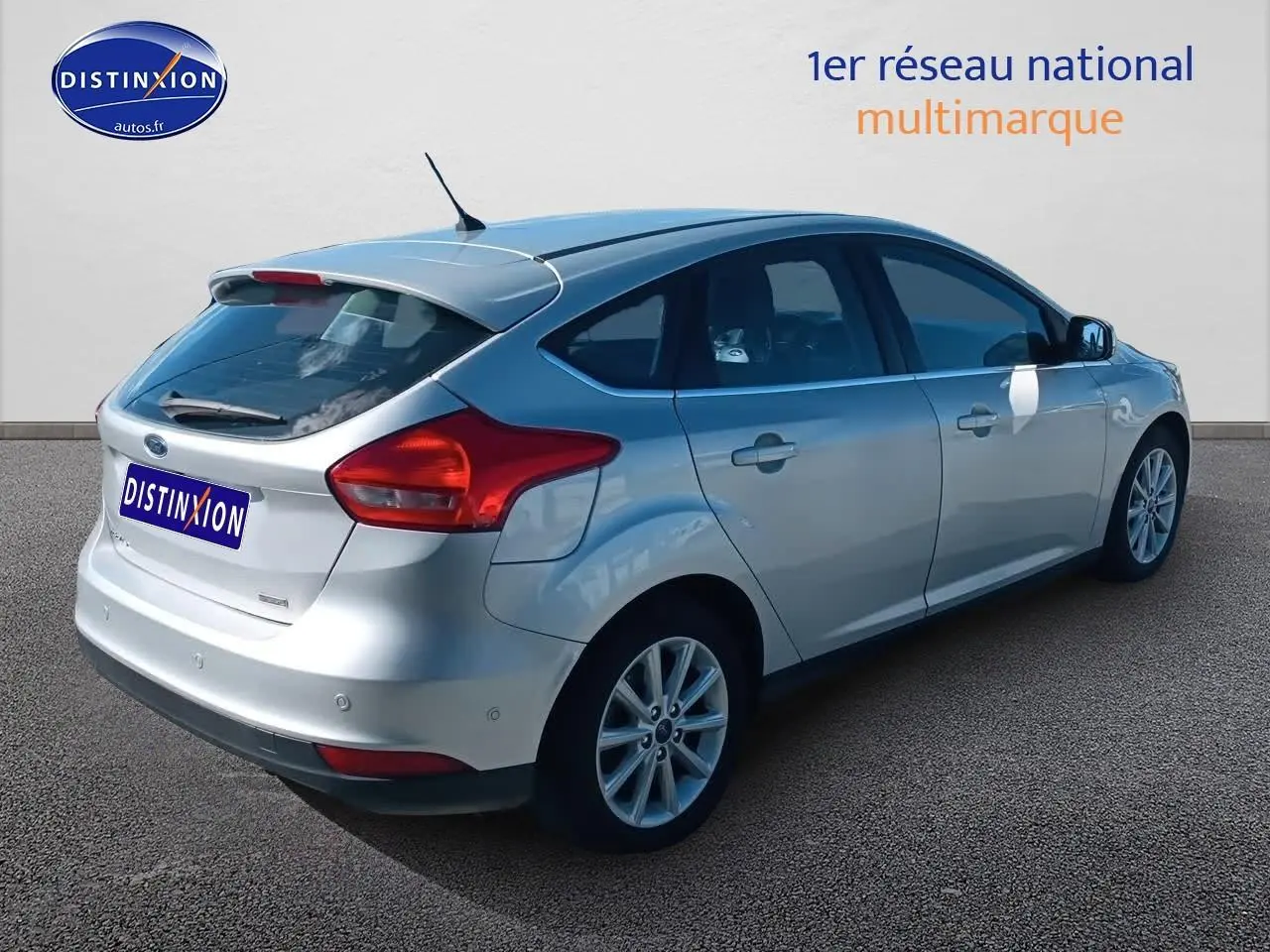 Ford Focus gris clair vue 3/4 arrière droit avec becquet et jantes alliage sur fond neutre