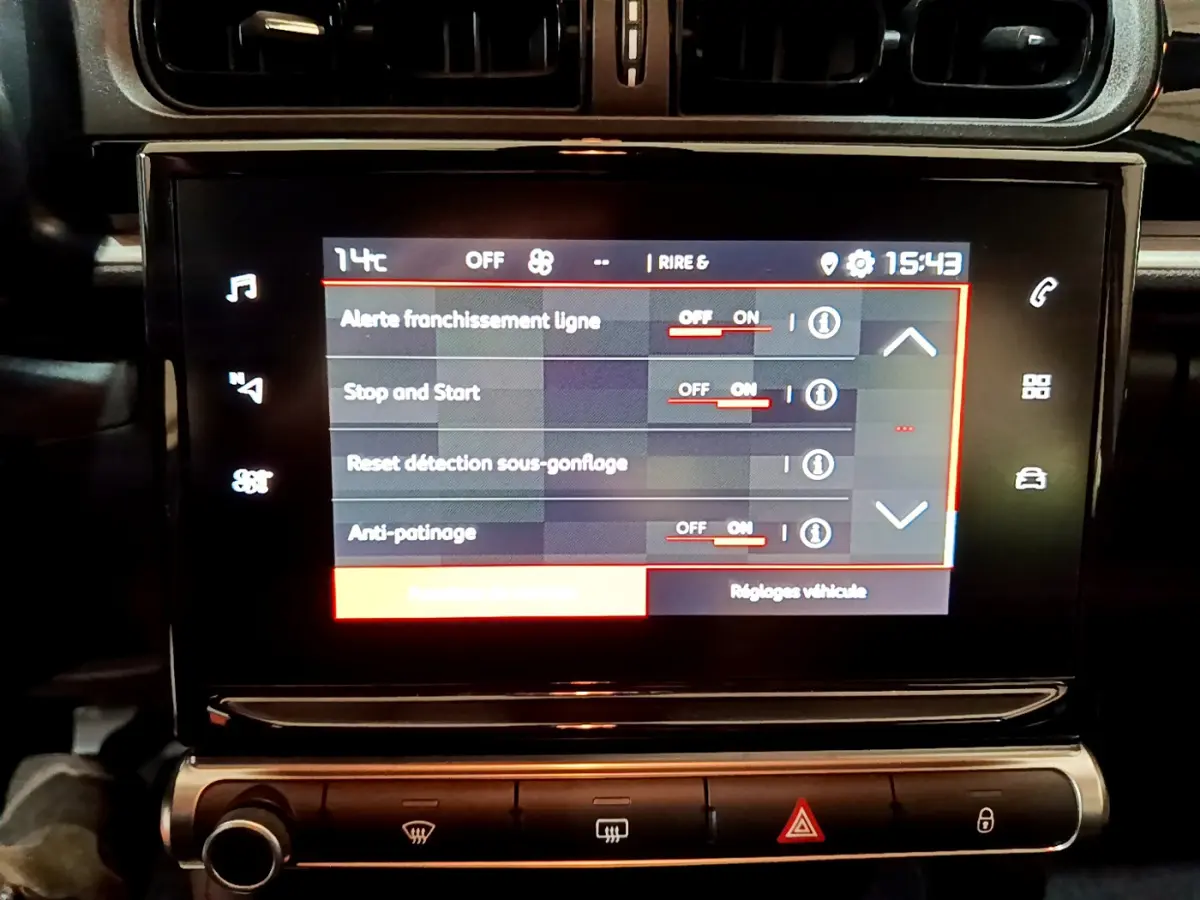 Vue rapprochée de l’écran tactile central noir du tableau de bord beige de la Citroën C3 2022 affichant les réglages d’aide à la conduite.