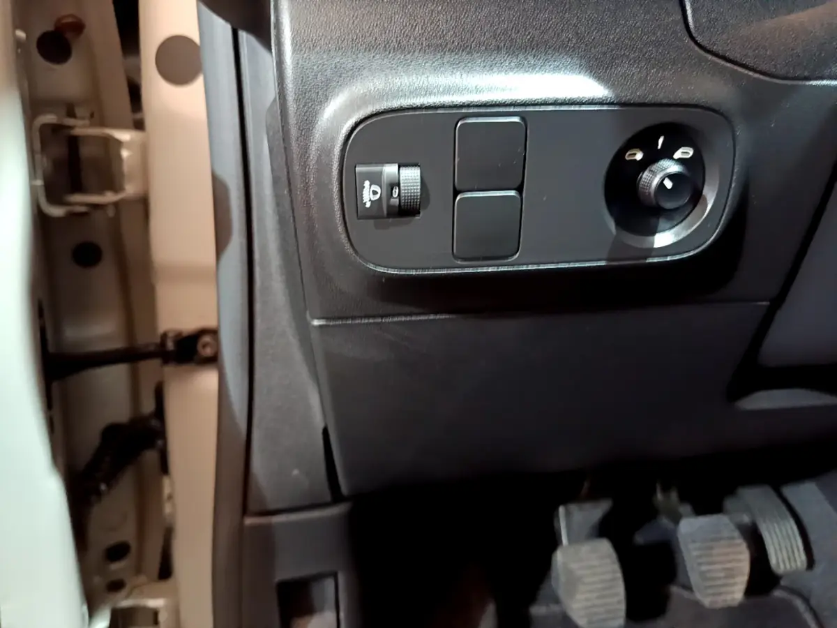 Vue rapprochée des commandes noires côté gauche sous le tableau de bord beige de la Citroën C3 2022.