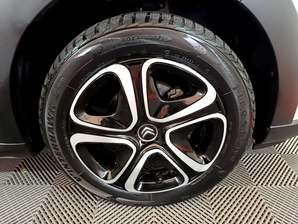 Gros plan sur la roue avant droite d'une Citroën C3 beige, montrant le pneu Firestone et l'aile noire.