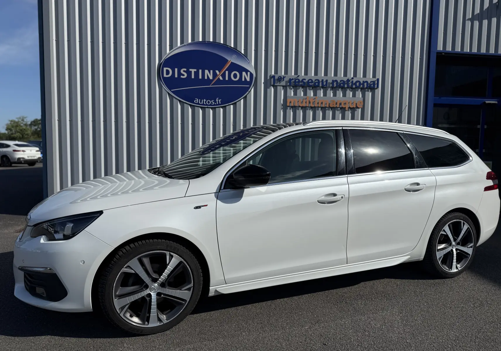 Peugeot 308 SW blanc nacré vue de profil côté gauche, avec jantes alliage distinctives et vitres teintées.