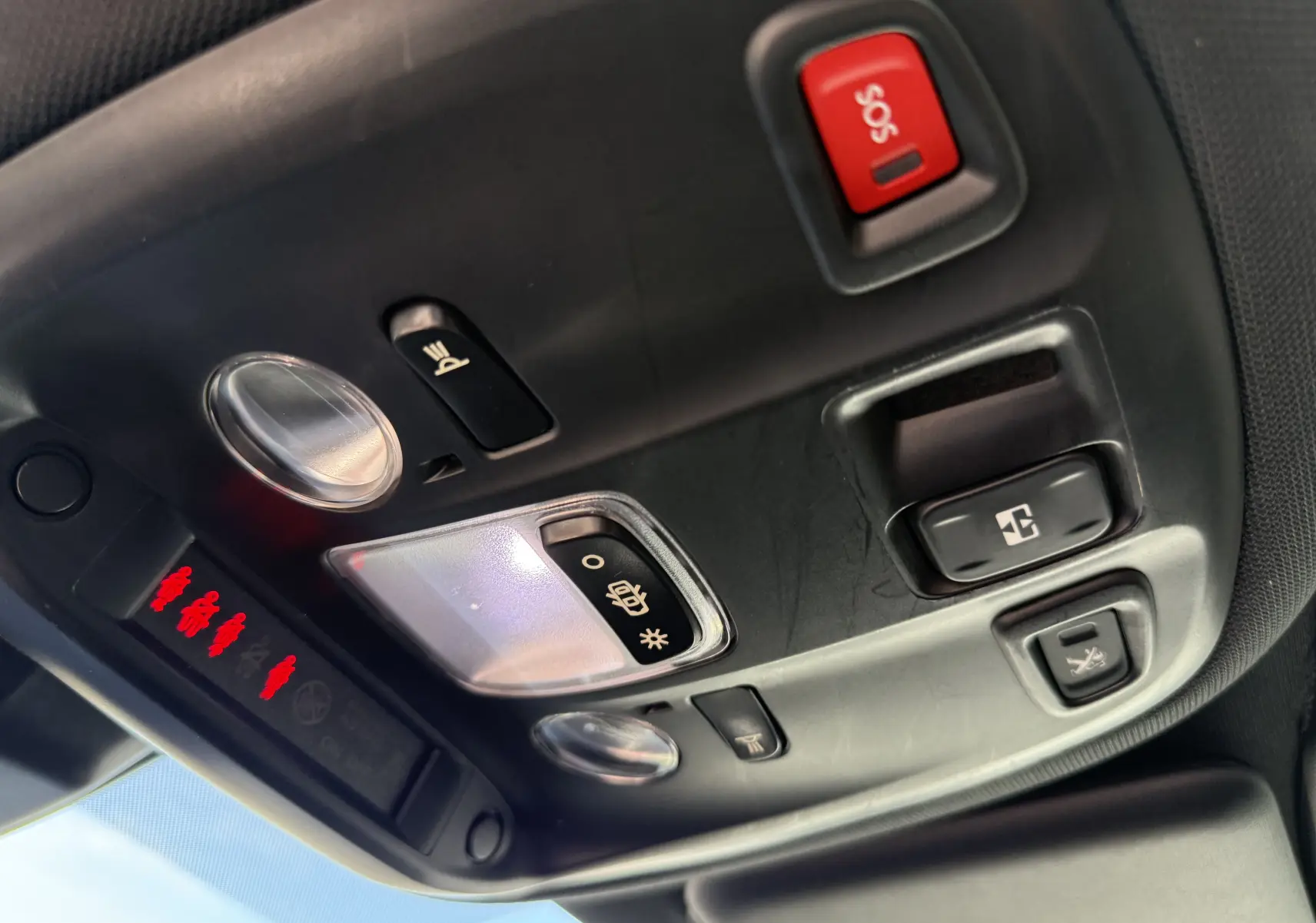 Vue en gros plan du plafonnier intérieur noir du Peugeot 308 SW blanc nacré avec boutons SOS et éclairage.