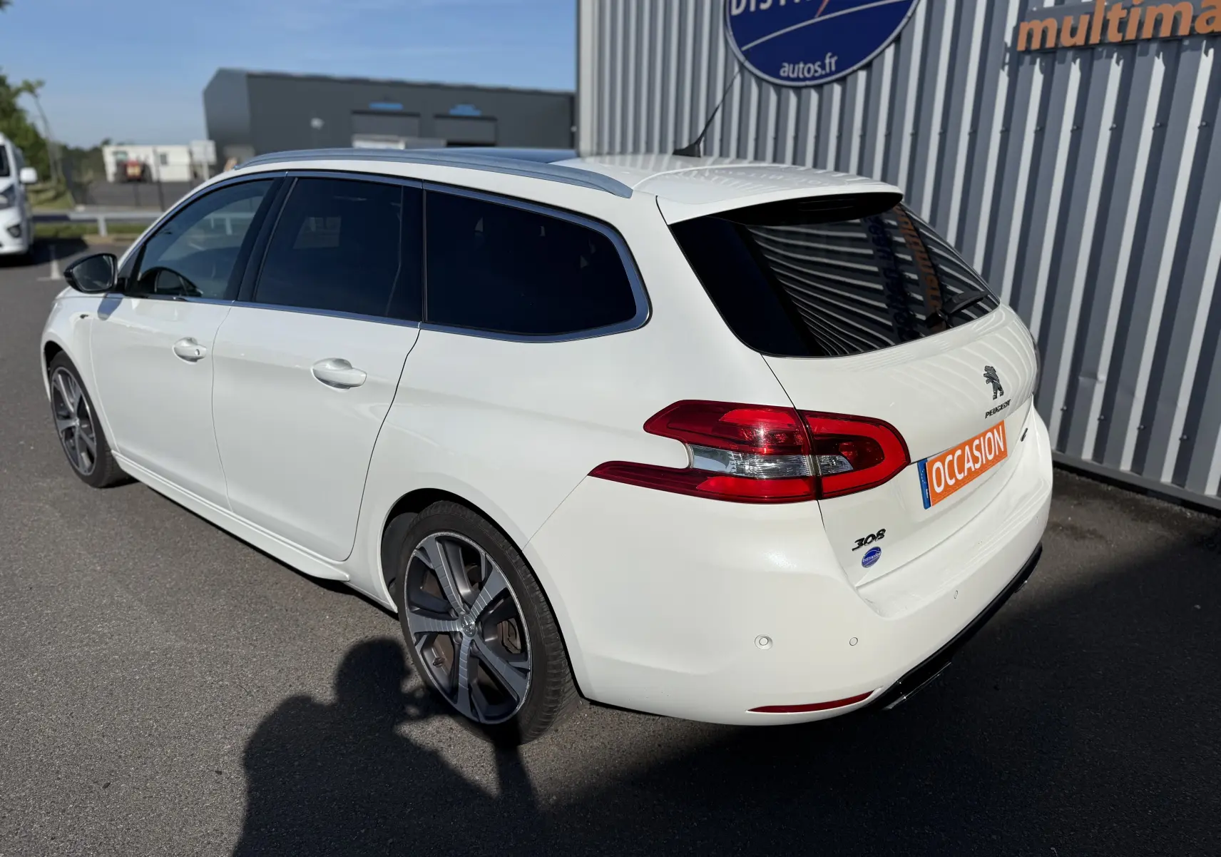 Peugeot 308 SW blanc nacré vue 3/4 arrière droit, break diesel avec vitres teintées et jantes alliage.