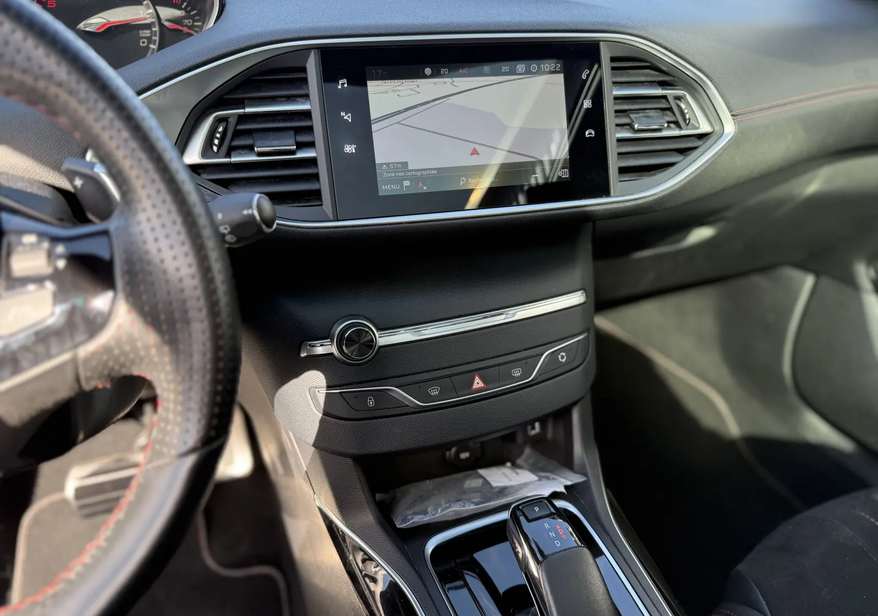 Vue intérieure centrée sur la console centrale et l’écran tactile de la Peugeot 308 SW, volant partiellement visible à gauche.