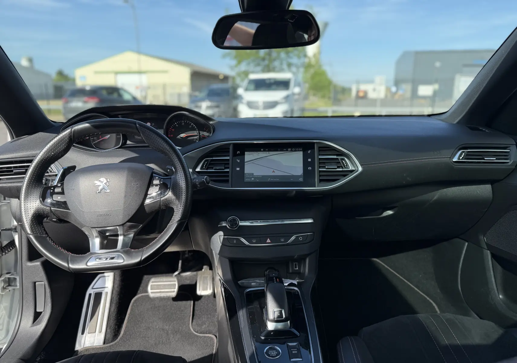 Vue intérieure avant de la Peugeot 308 SW 1.5 BlueHDi GT 2021, tableau de bord noir avec écran tactile et volant GT.