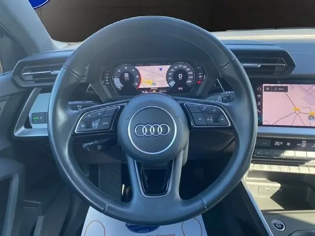 Vue centrée sur le volant cuir noir d'une Audi A3 30 TDI 116 Business Line 2021 avec tableau de bord numérique et écran tactile.