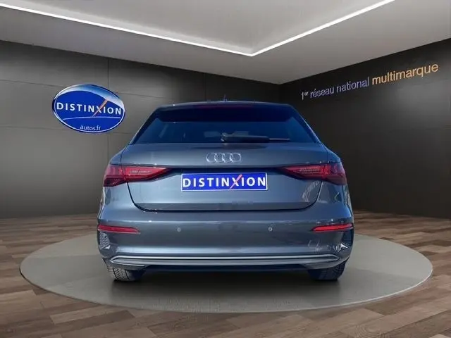 Vue arrière d'une Audi A3 30 TDI Business Line gris foncé, avec feux LED et logo Audi visible, sur plateau showroom.