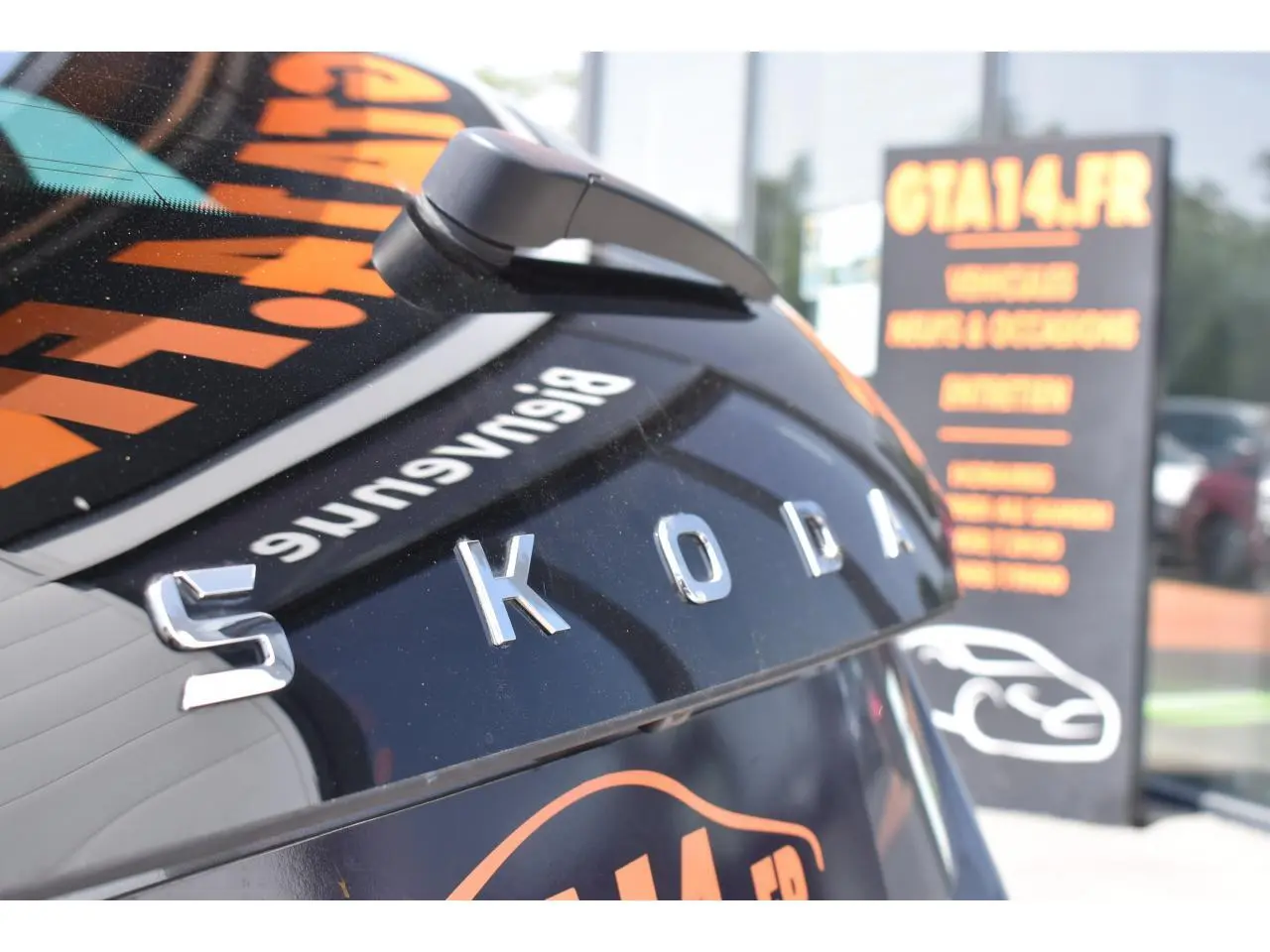 Gros plan sur l'arrière d'une Skoda Scala gris graphite métallisé avec logo SKODA en relief et caméra de recul visible.