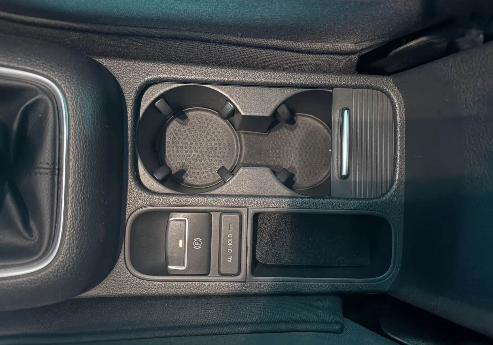 Vue rapprochée de la console centrale noire du Volkswagen Tiguan 2.0 TDI avec porte-gobelets et commandes électroniques.