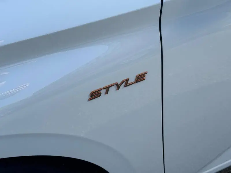 Gros plan sur l’inscription Style en relief couleur cuivre sur la porte blanche Okénite d’une Peugeot 308 2025.