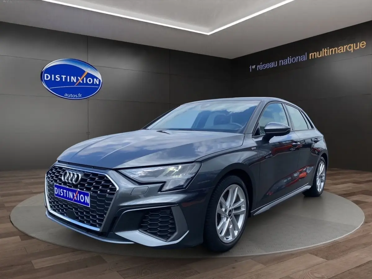Audi A3 30 TFSI S Line gris foncé vue 3/4 avant dans un showroom avec éclairage intérieur.