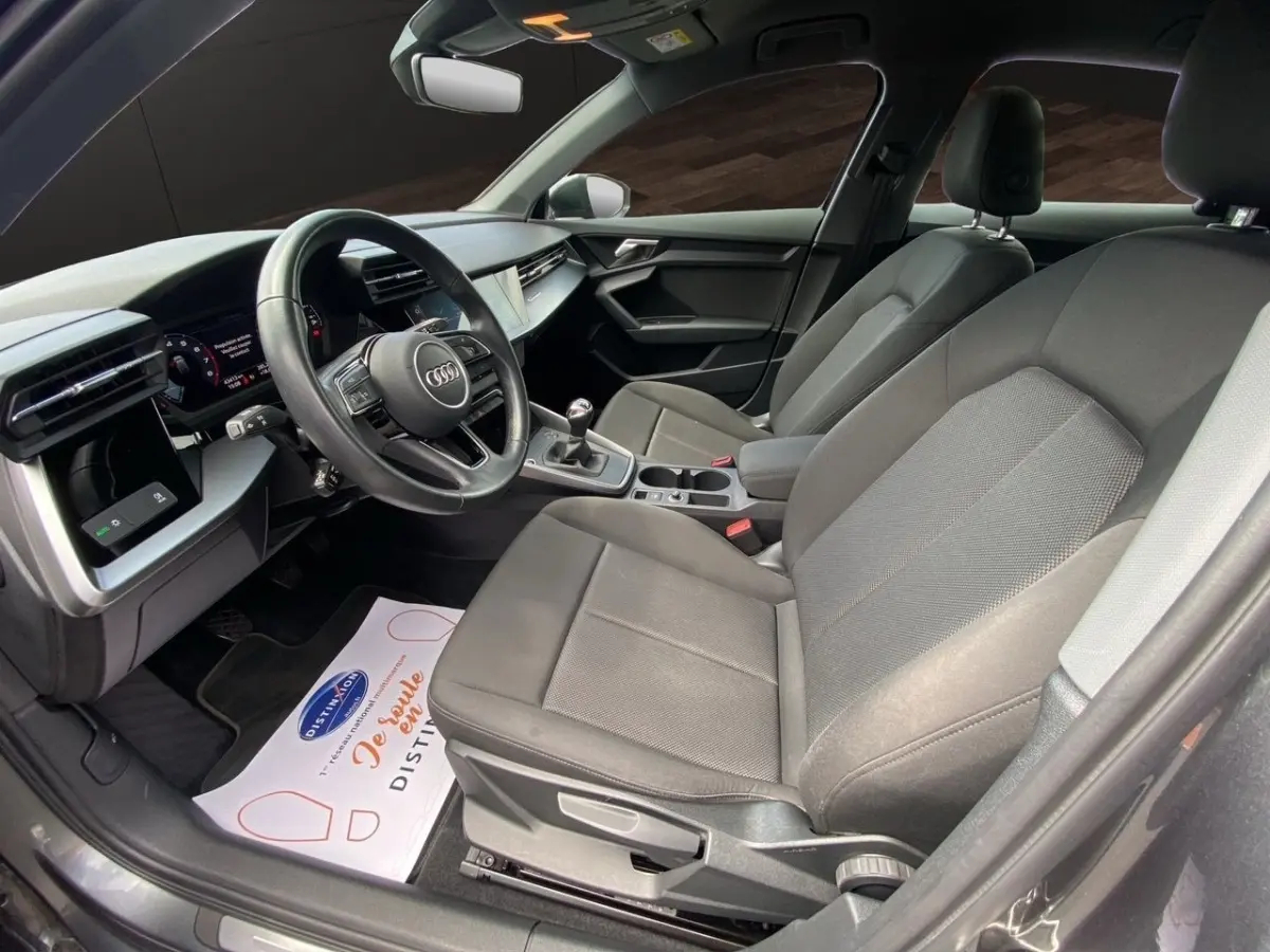 Vue intérieure côté conducteur de l’Audi A3 30 TFSI S Line 2021 gris foncé, volant cuir et console centrale avec boîte manuelle.