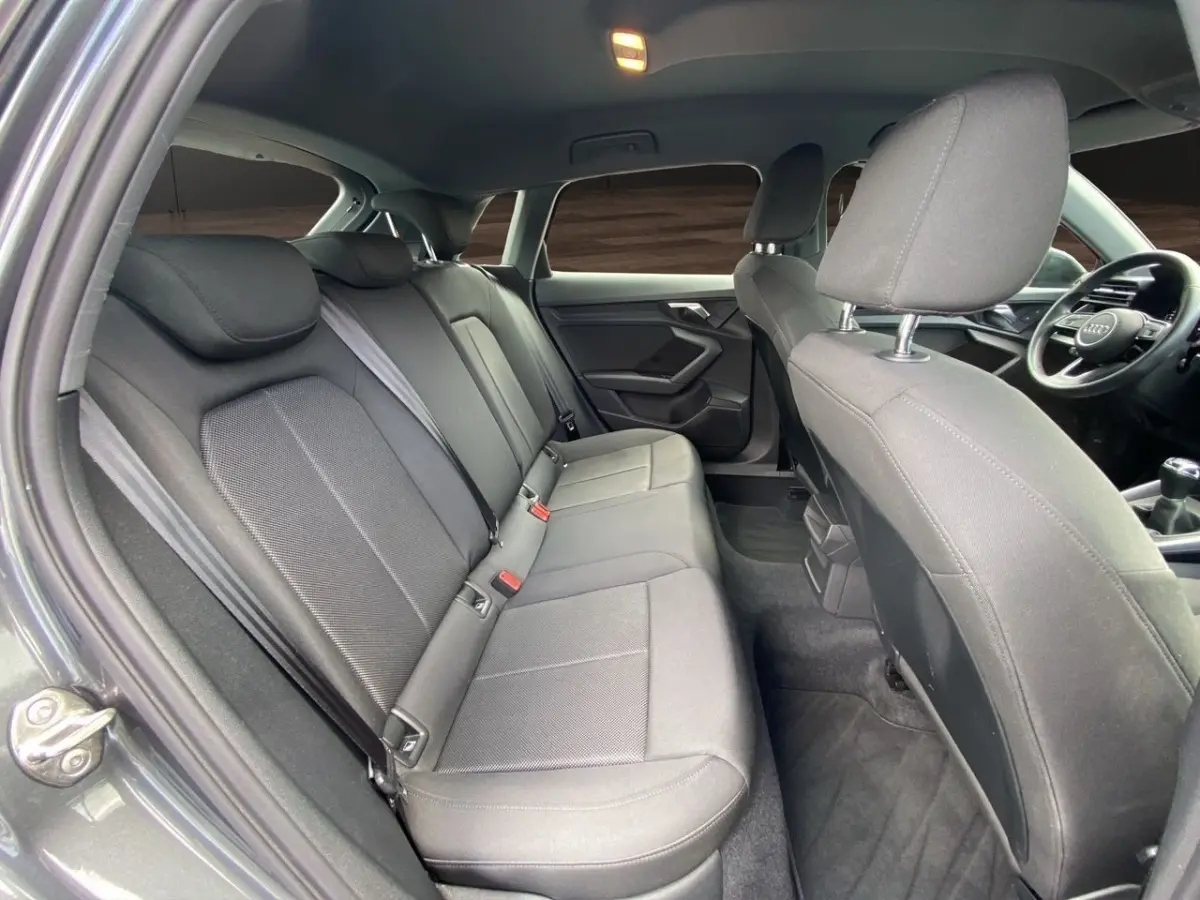 Vue intérieure côté gauche montrant la banquette arrière et les sièges avant gris foncé de l'Audi A3 30 TFSI S Line 2021.