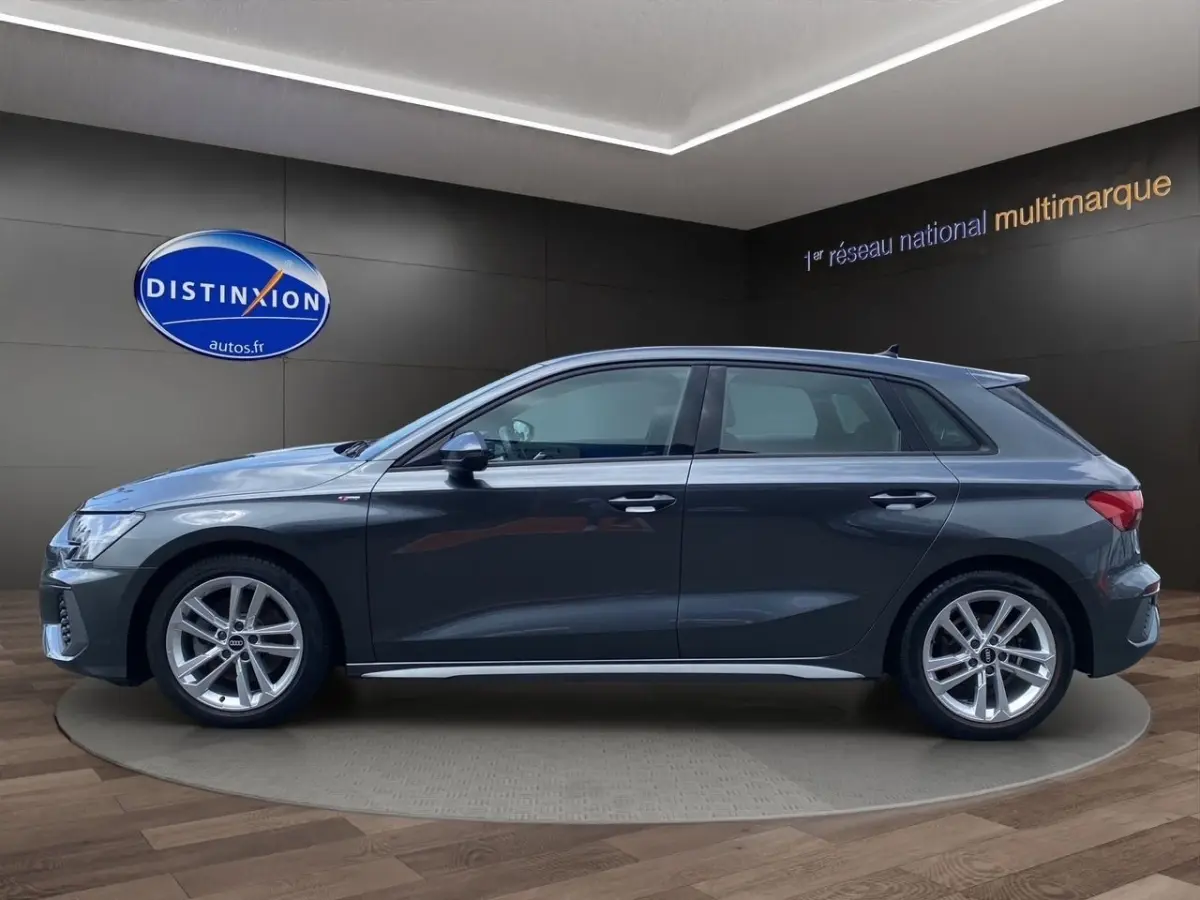 Profil côté gauche d'une Audi A3 30 TFSI S Line gris foncé, avec jantes alliage et rétroviseurs électriques rabattables.