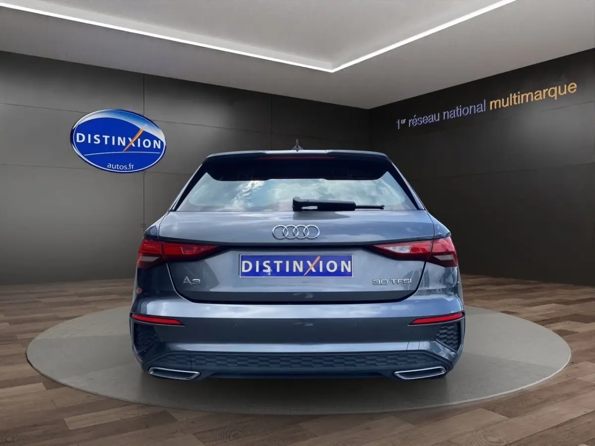 Vue arrière d'une Audi A3 30 TFSI gris foncé avec double sortie d'échappement et logo distinctif sur coffre.