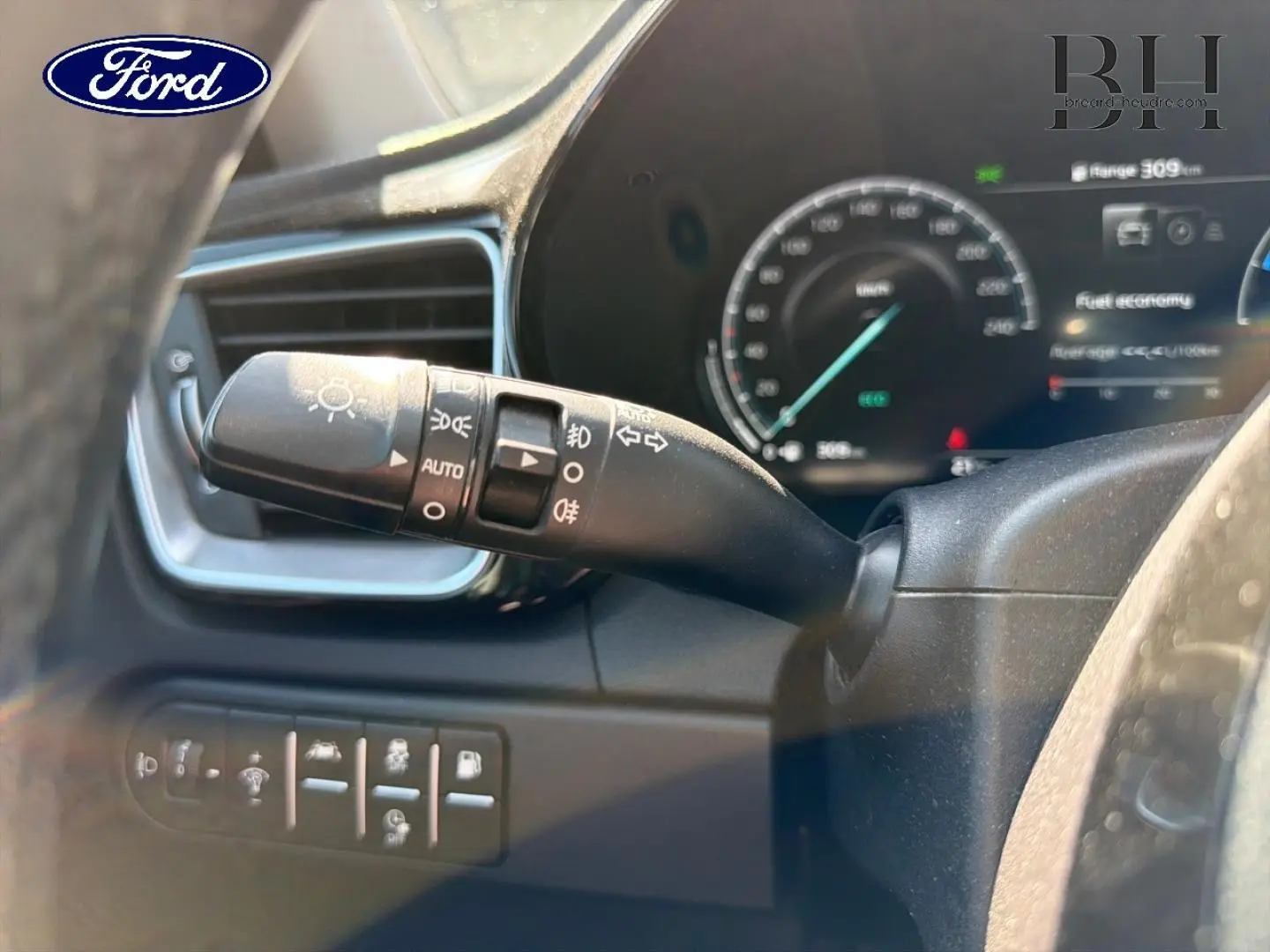 Gros plan sur la manette de commandes d’éclairage et clignotants côté gauche du volant d’une KIA Xceed noire.