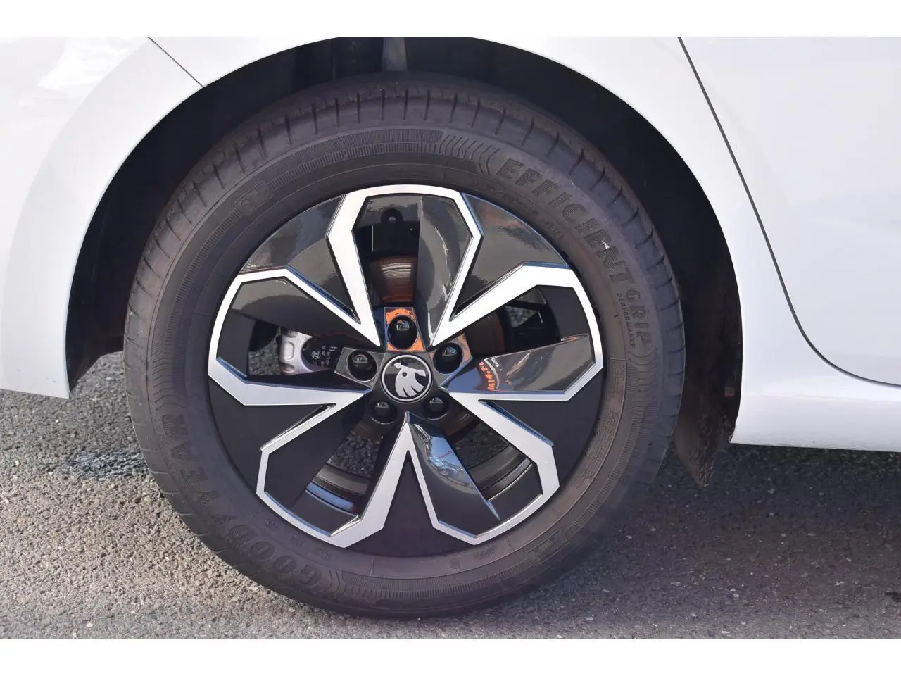 Gros plan sur la roue avant droite d'une Skoda Scala blanc glacier avec jante noire et argentée au design géométrique.