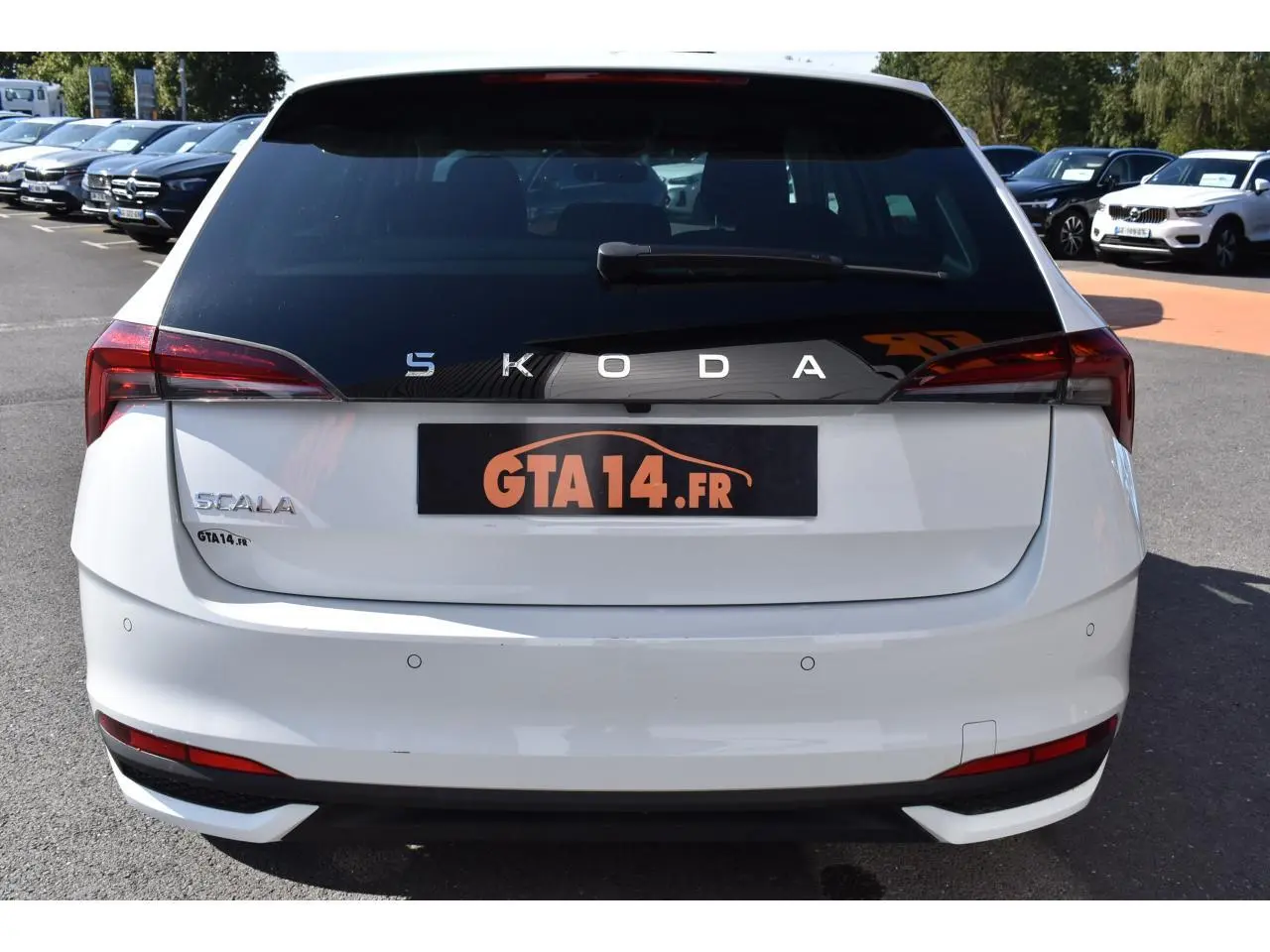 Vue arrière d'une Skoda Scala blanche glacier avec logo SKODA en lettres espacées sur la lunette arrière noire.