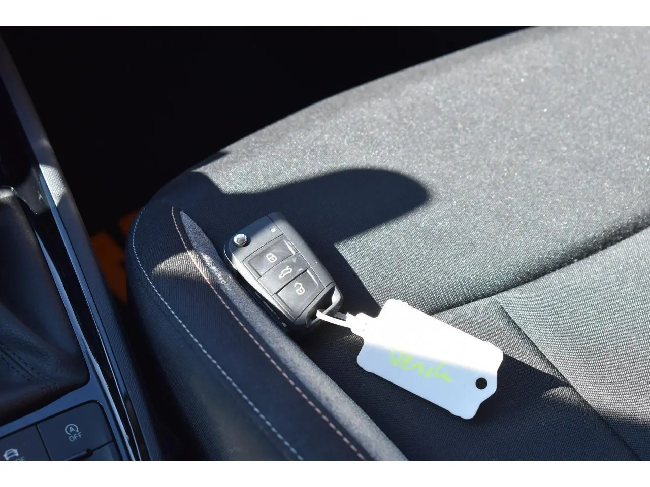 Gros plan sur la clé noire posée sur le siège tissu noir à surpiqûres blanches, intérieur d’une Skoda Scala blanc glacier.
