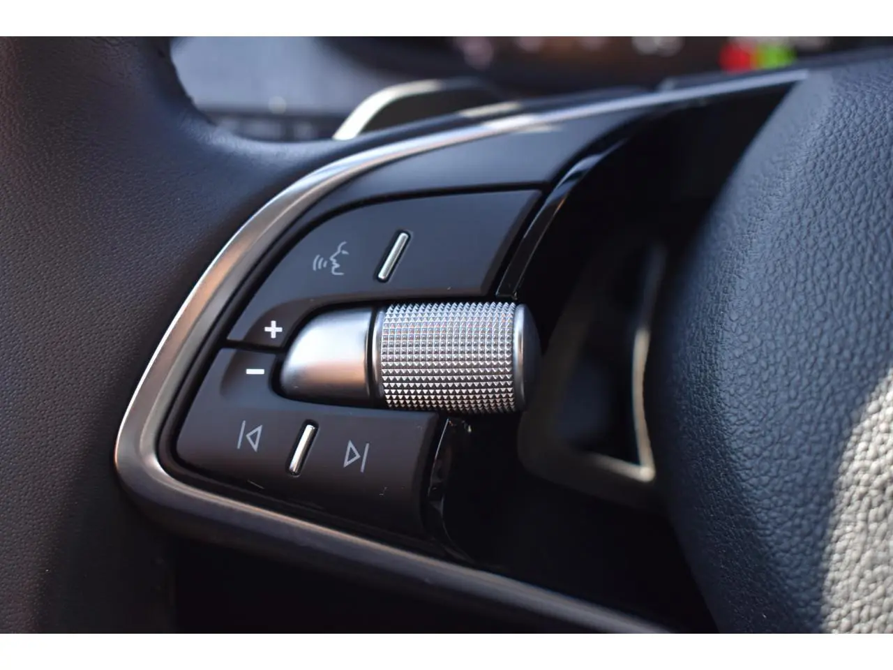 Gros plan sur les commandes multifonctions à gauche du volant cuir de la Skoda Scala 2025, finition noire et chrome.