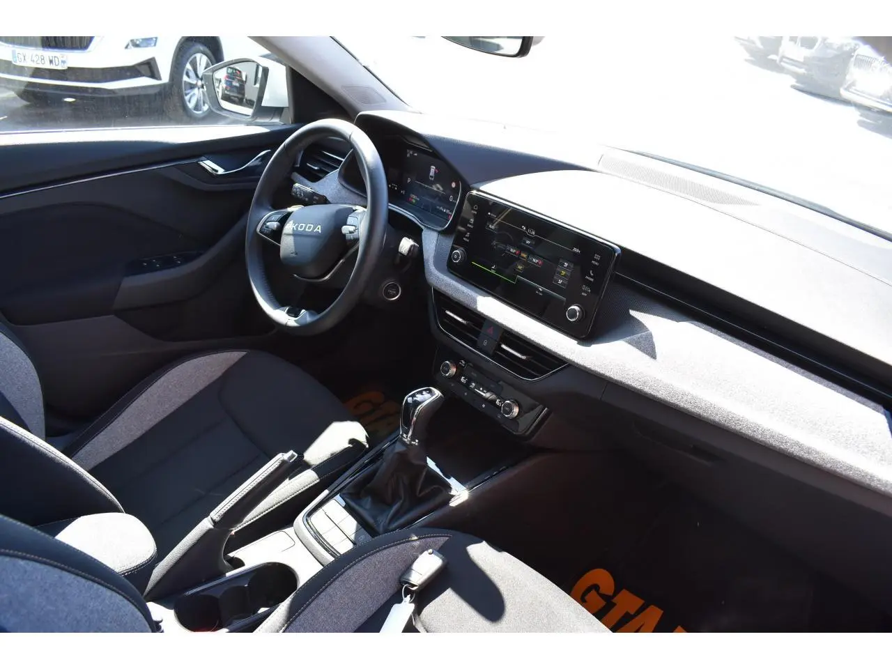 Vue intérieure côté conducteur de la Skoda Scala 2025, avec tableau de bord gris suédine et sellerie tissu noir et gris.