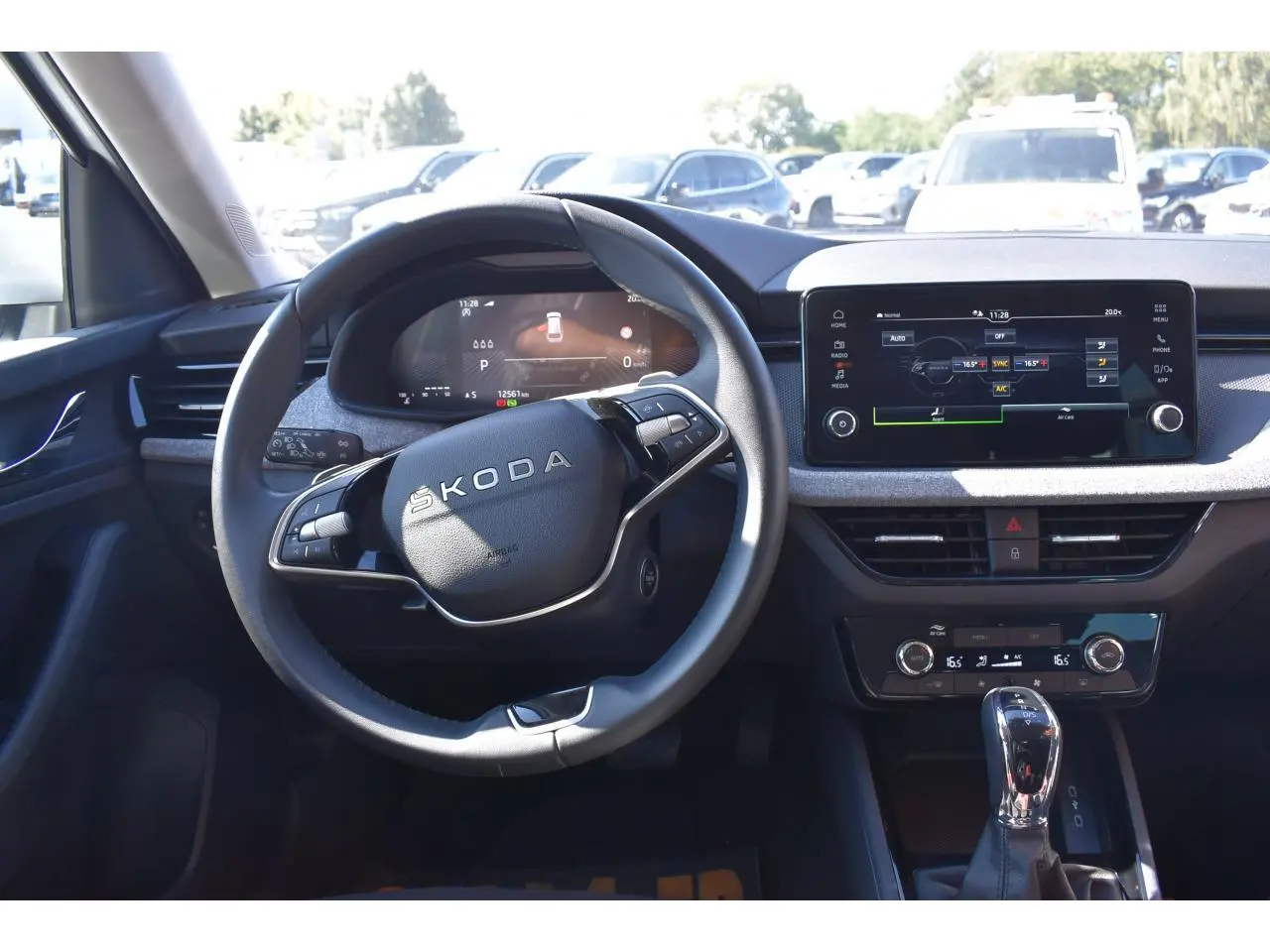 Vue intérieure centrée sur le volant Skoda et la planche de bord avec écran tactile et levier de vitesse.
