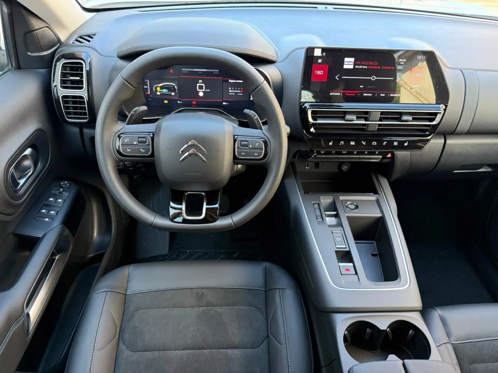 Vue intérieure frontale du tableau de bord du Citroën C5 Aircross blanc banquise 2024, avec écran tactile et volant multifonction.