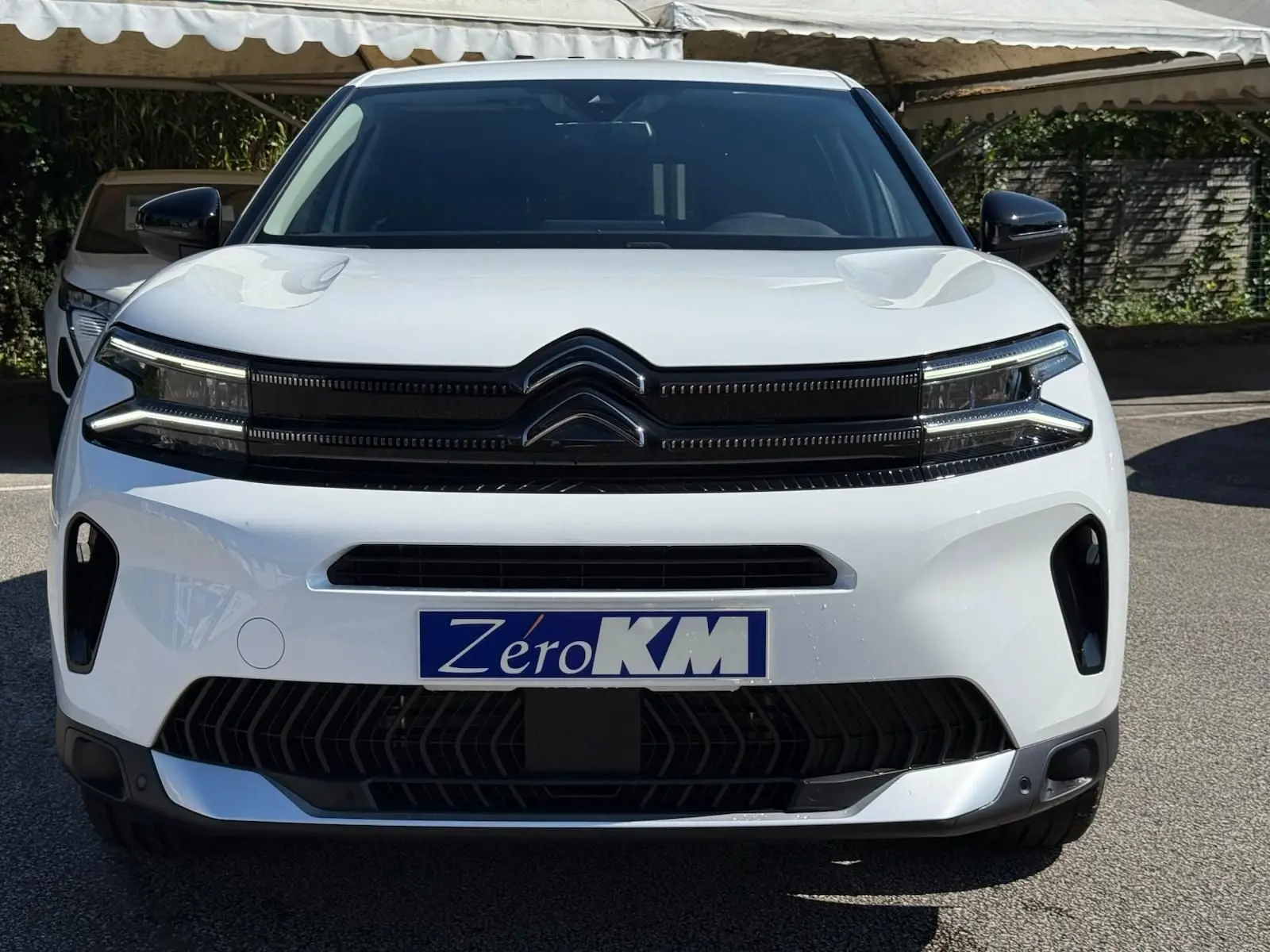 Vue de face d'un Citroën C5 Aircross blanc banquise 2024 avec calandre noire et plaque Zéro KM visible.